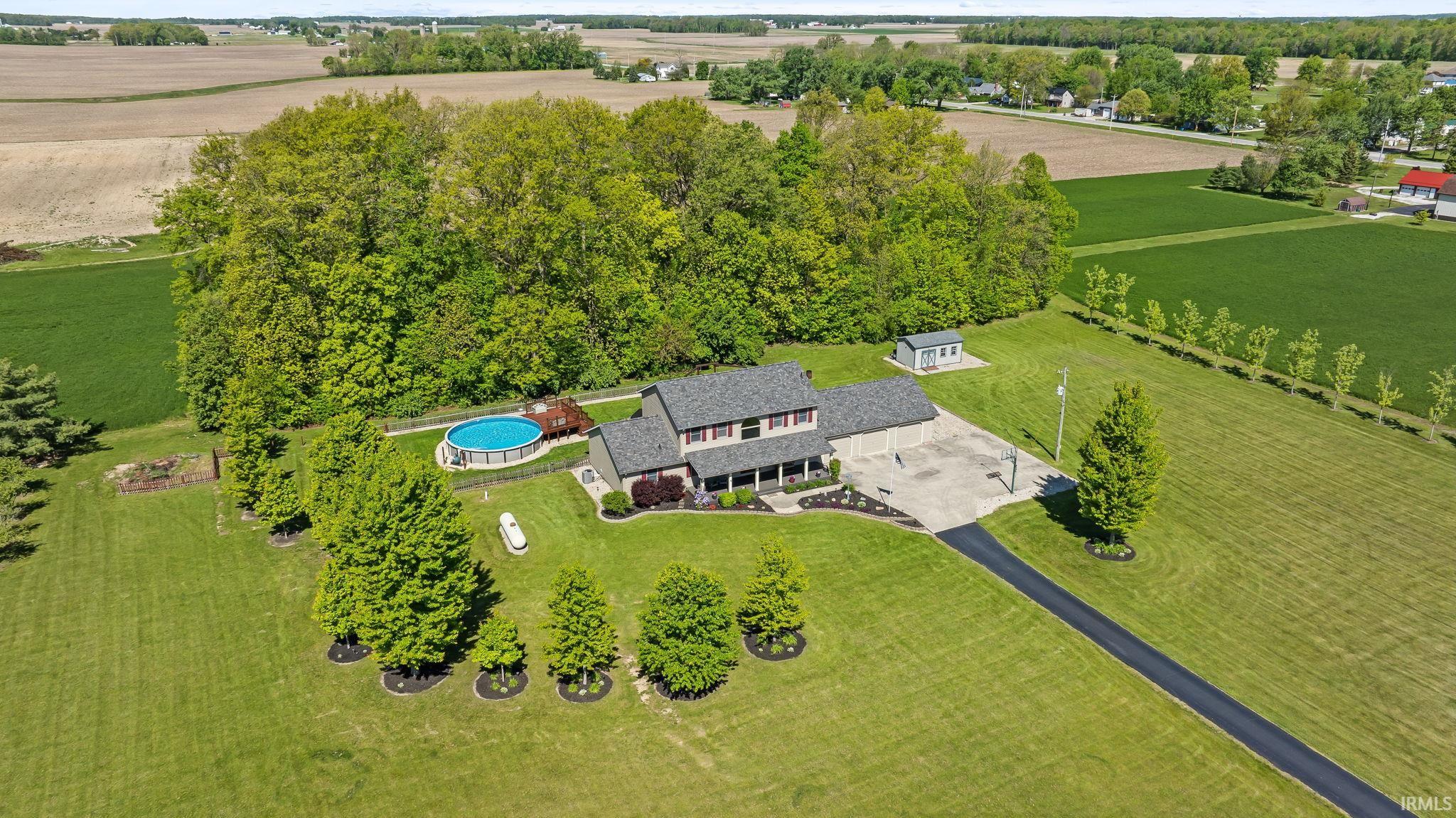 Sprawling property featuring a two-story residence with a covered front porch, a paved driveway, and an above-ground pool with an accompanying deck