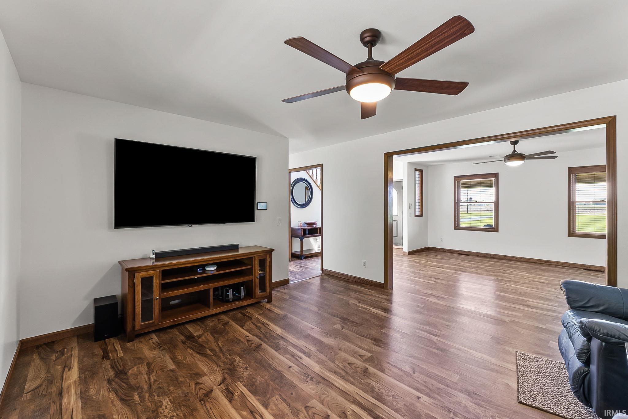 Spacious interior featuring wood-finish flooring, white walls, and a ceiling fan with integrated lighting
