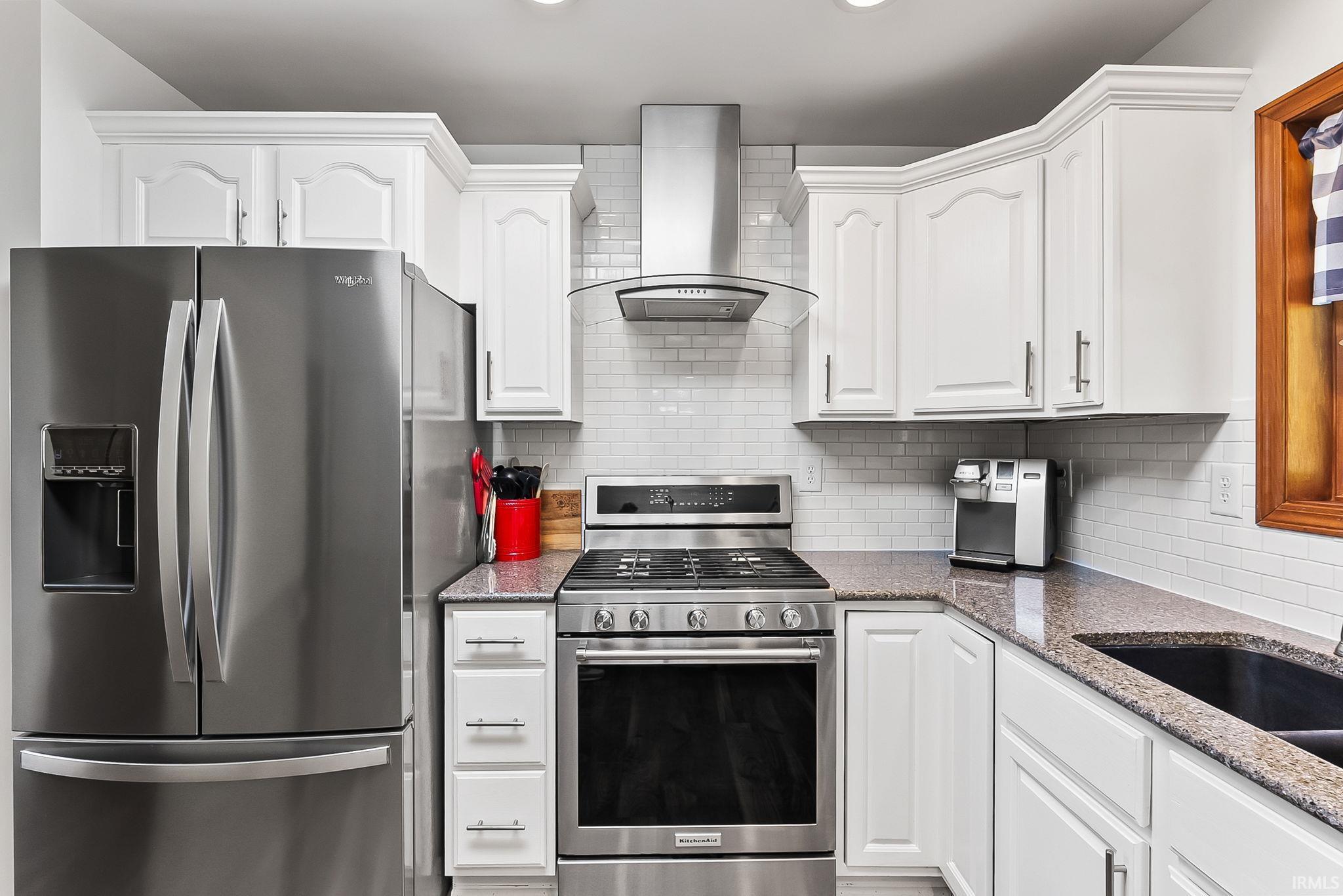 Kitchen featuring white cabinetry with crown molding, stainless steel appliances, speckled stone countertops, and a subway tile backsplash