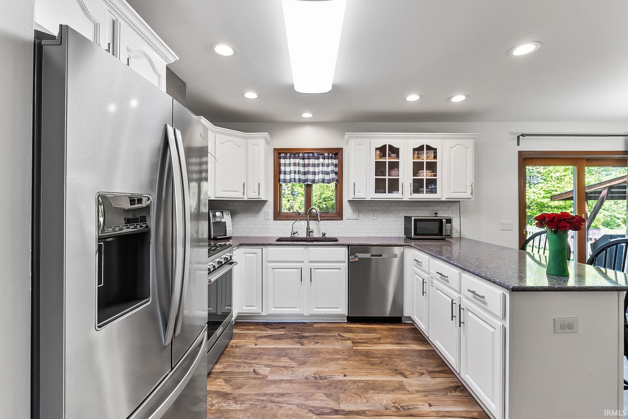 Kitchen with white cabinetry and dark speckled countertops