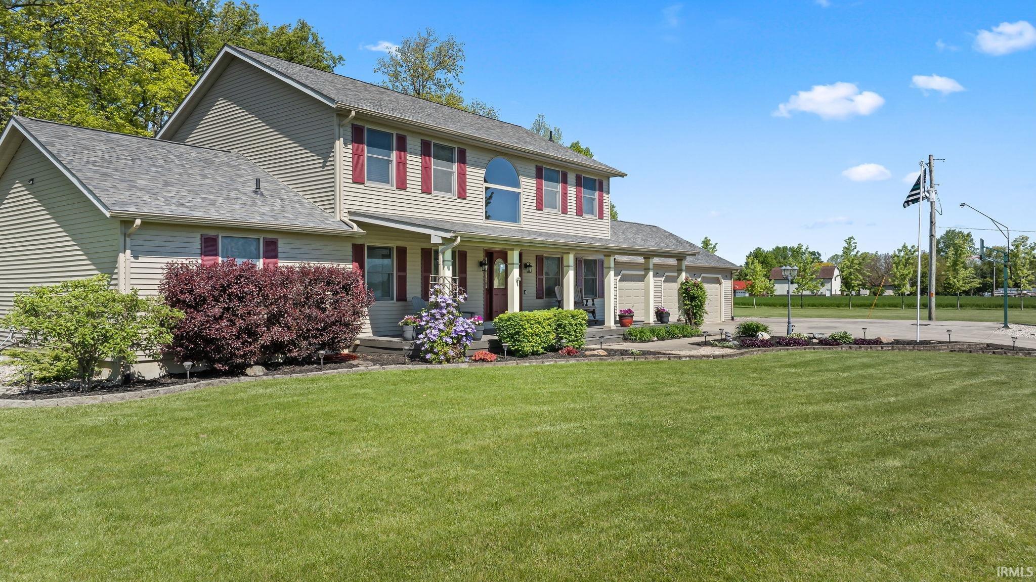 Two-story residence featuring light-toned siding, a multi-gabled roofline, and red window shutters