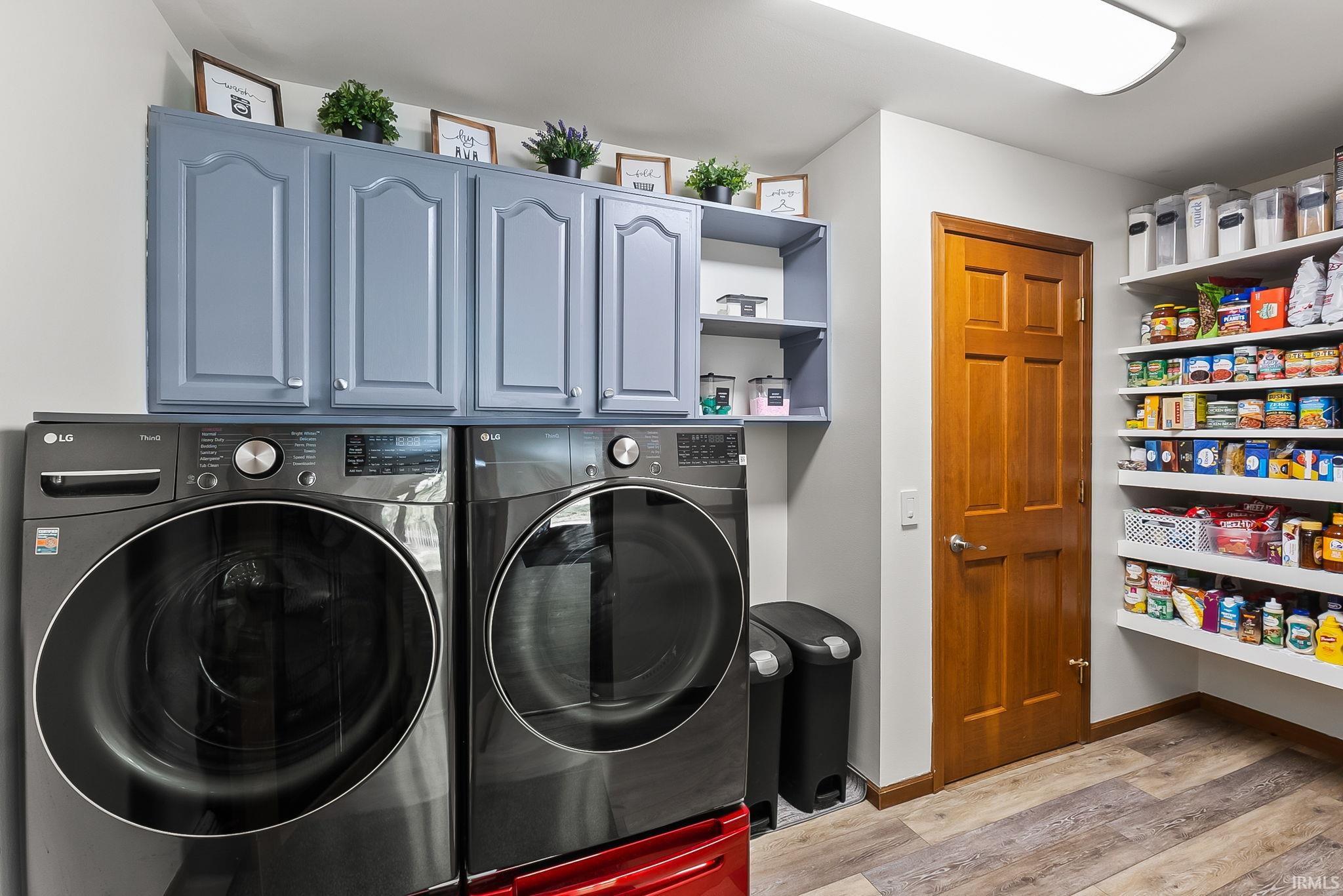 Dedicated laundry area featuring a washer and dryer, light gray cabinetry, and open shelving