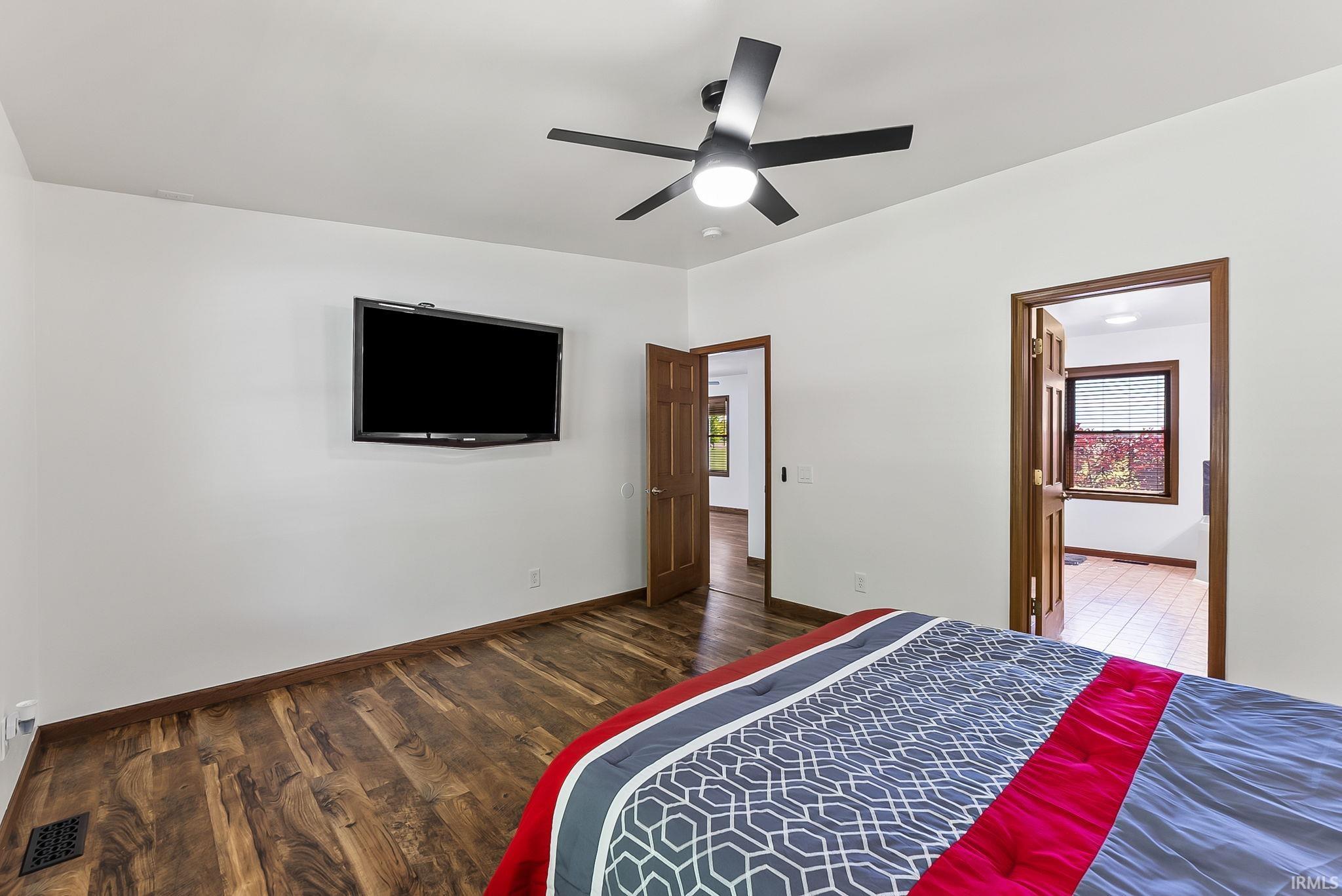 Room featuring wood-finish flooring, a ceiling fan with integrated lighting, and white walls