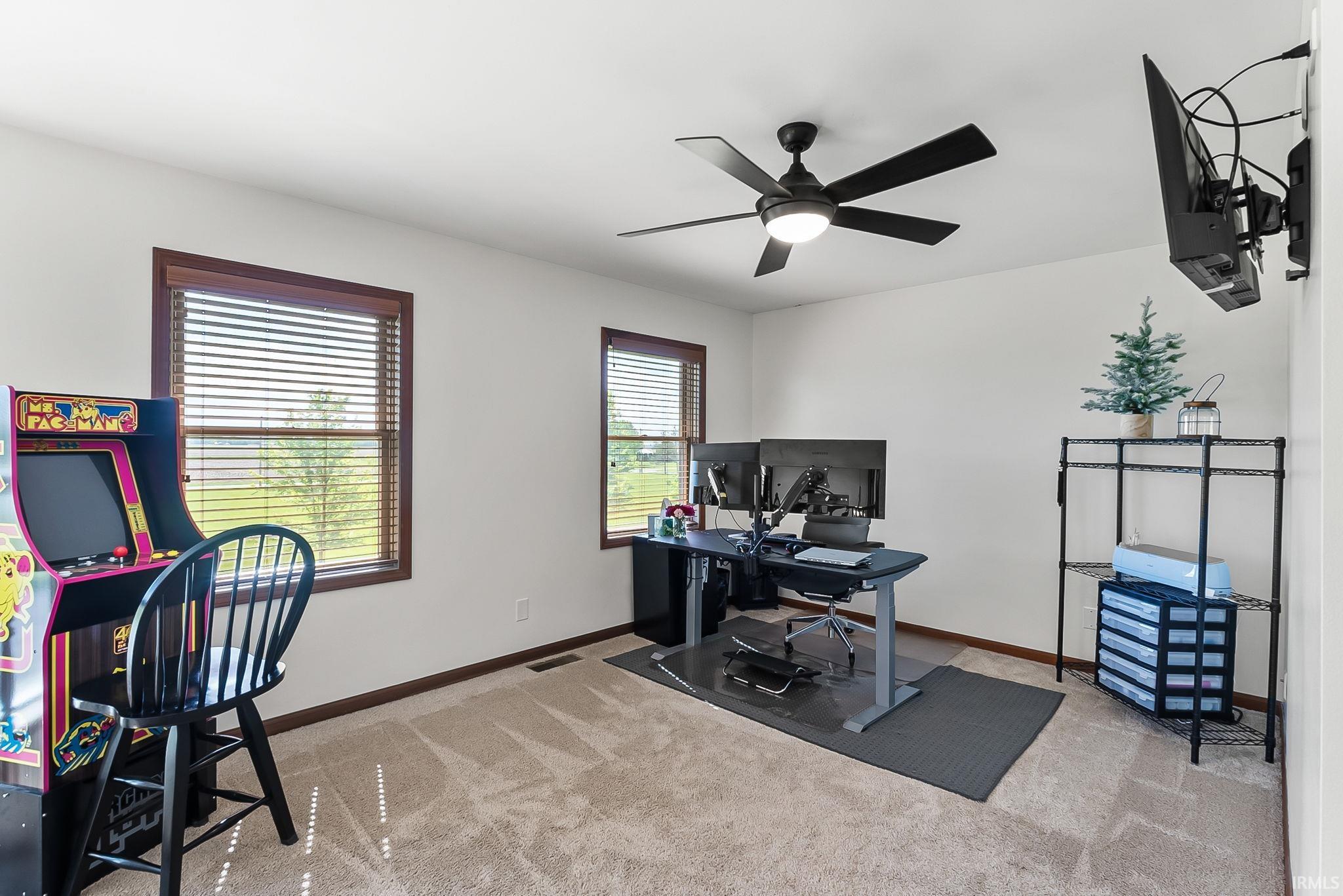 Neutral-toned carpeted room featuring white walls and two windows with wood-finish trim and blinds
