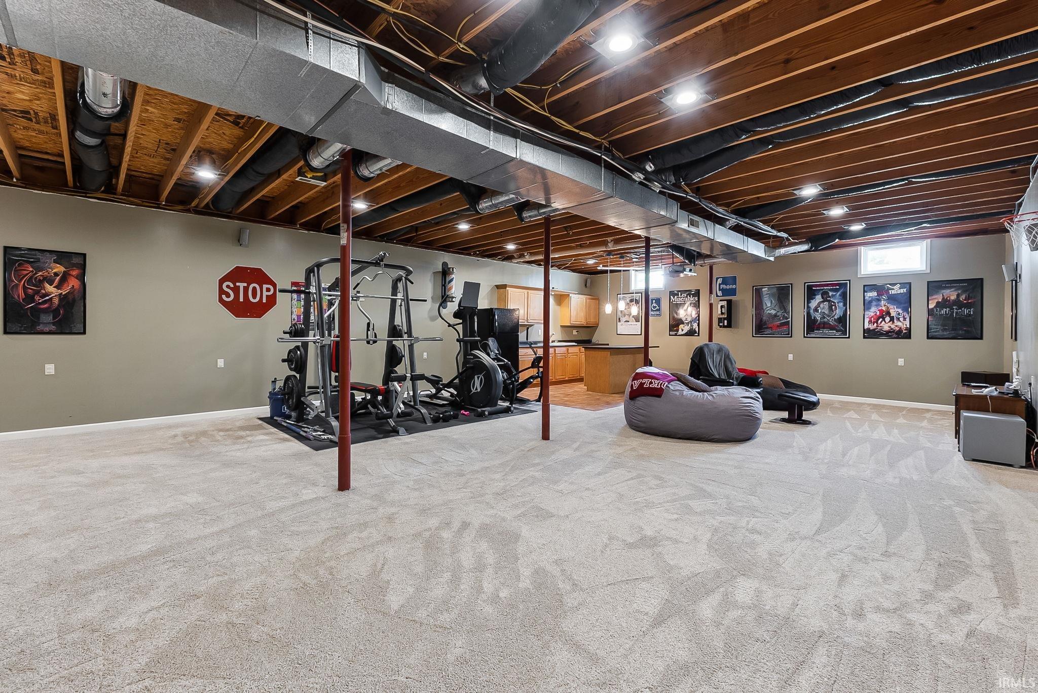 Expansive carpeted lower level with recessed lighting and exposed wood joist ceiling