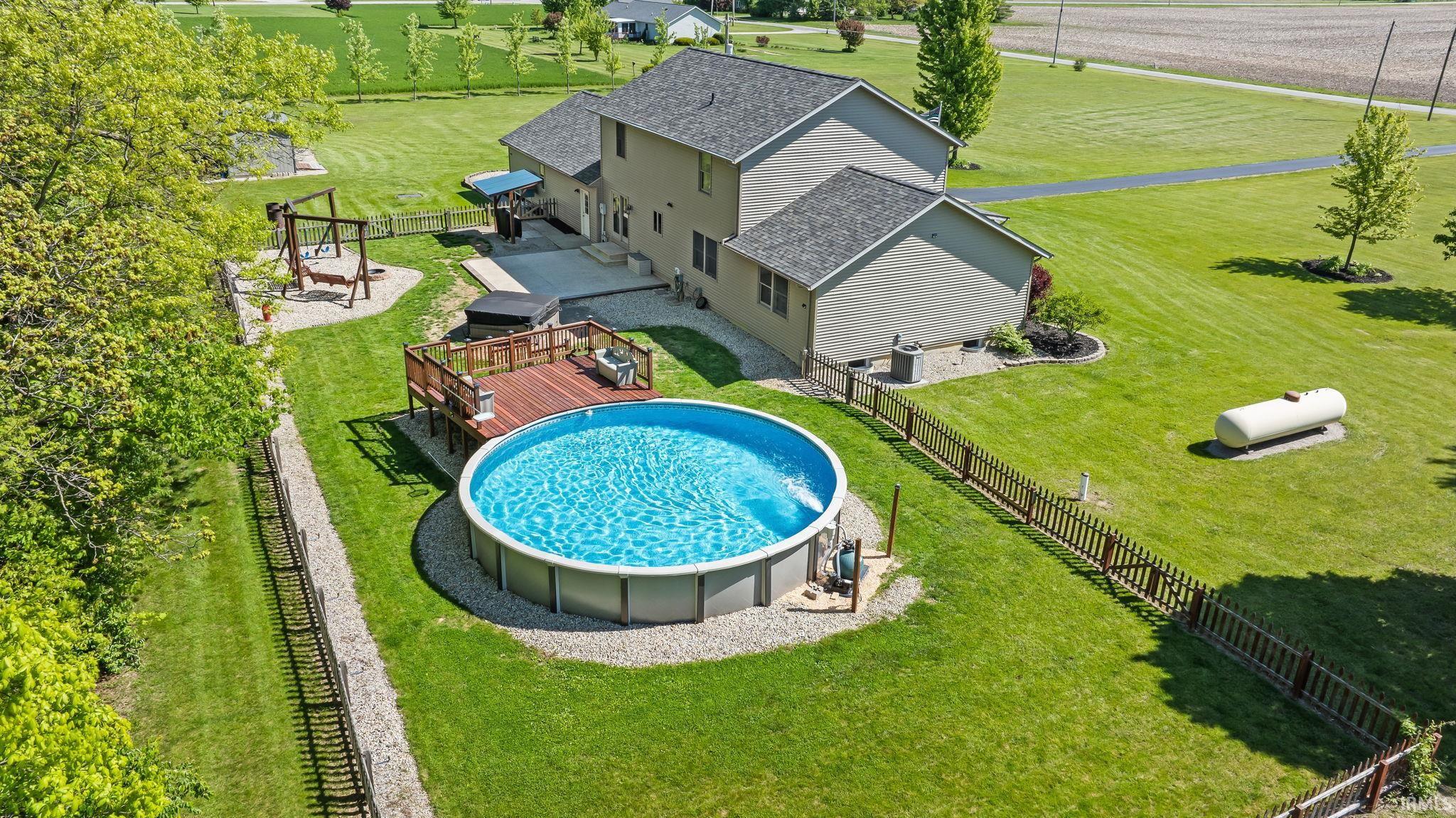 Expansive backyard featuring a large above-ground pool with an accompanying wood-finish deck