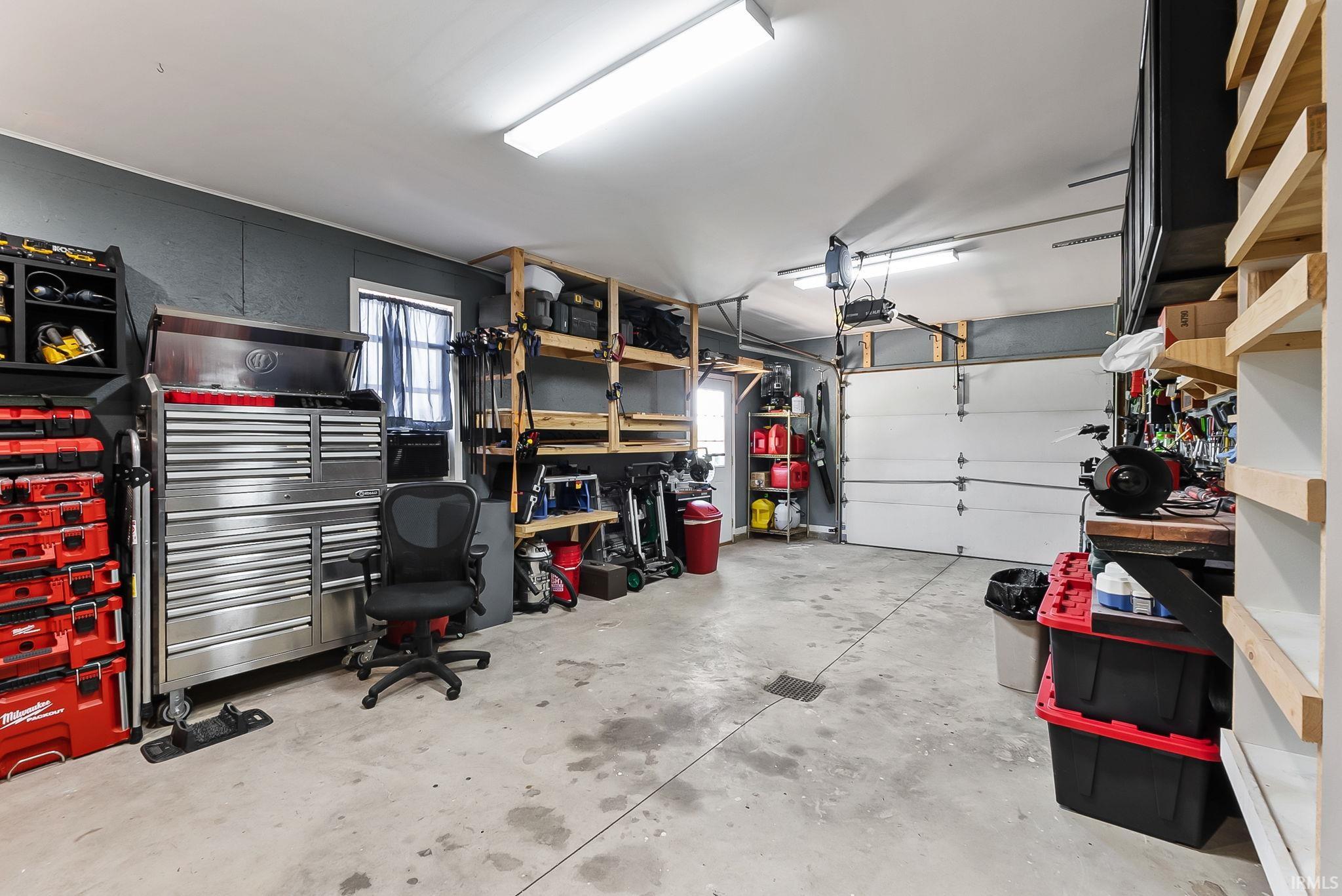 Spacious garage featuring a concrete floor, overhead lighting, and built-in shelving
