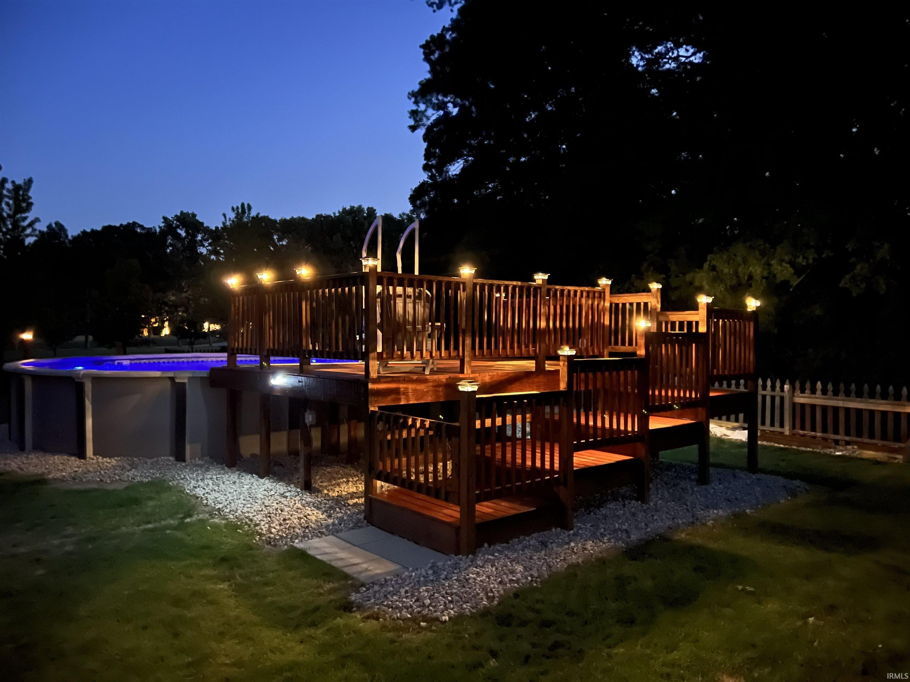 Tiered wood deck with integrated lighting, surrounding an above-ground pool