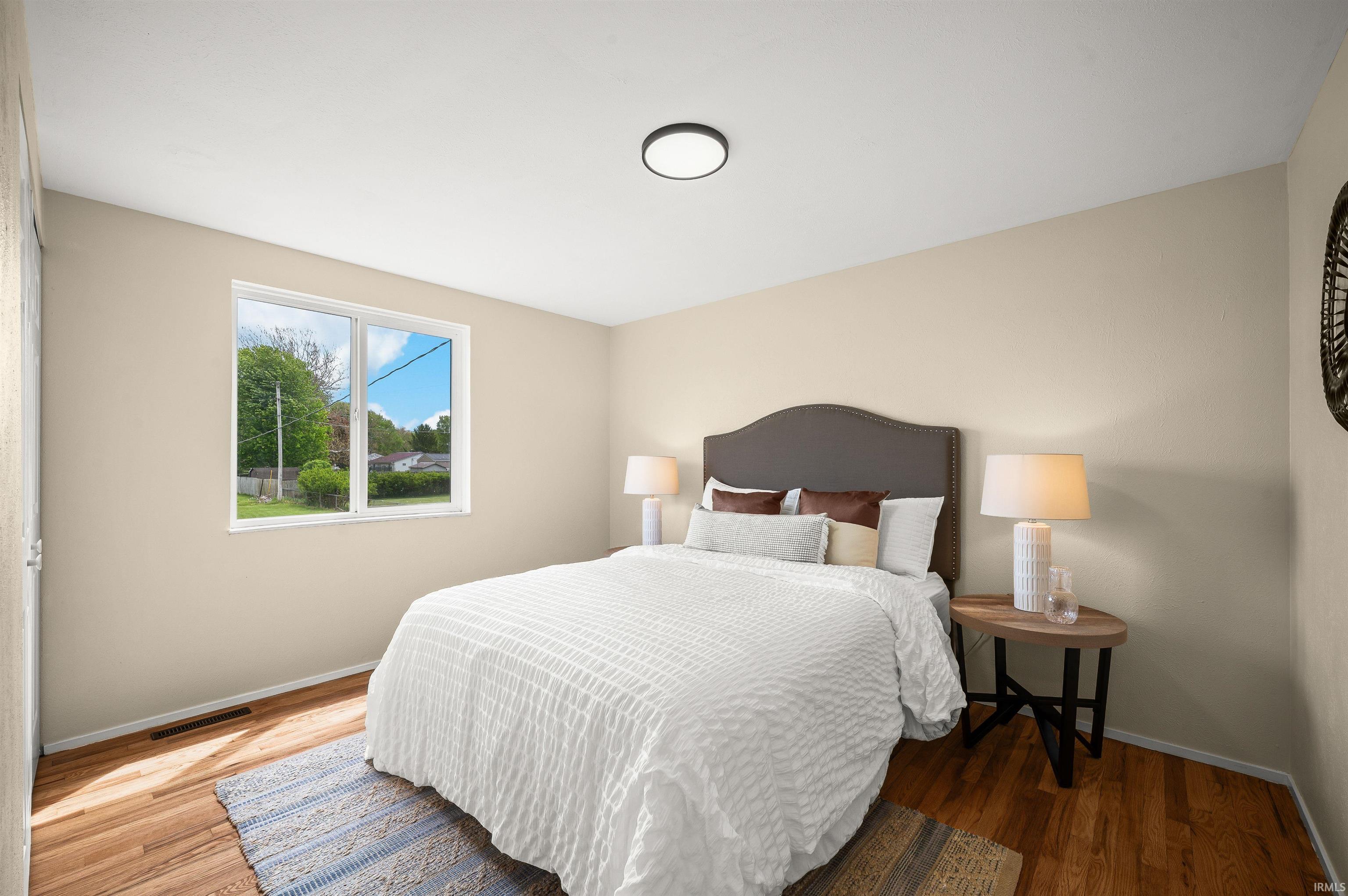 Bedroom featuring wood-finish flooring, a double window, and recessed lighting