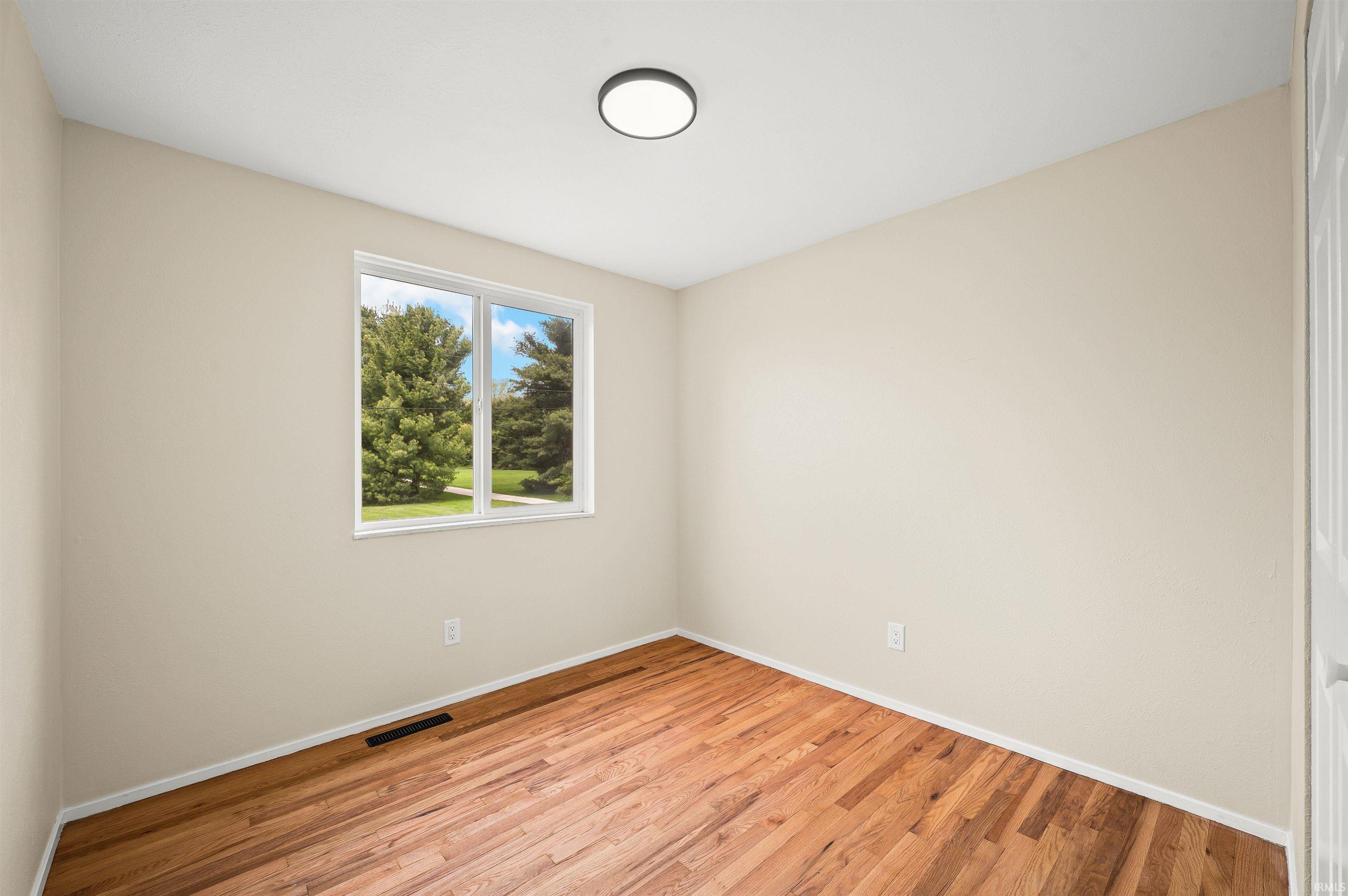 Room featuring wood-finish flooring, a double-pane window, and a flush-mount ceiling light
