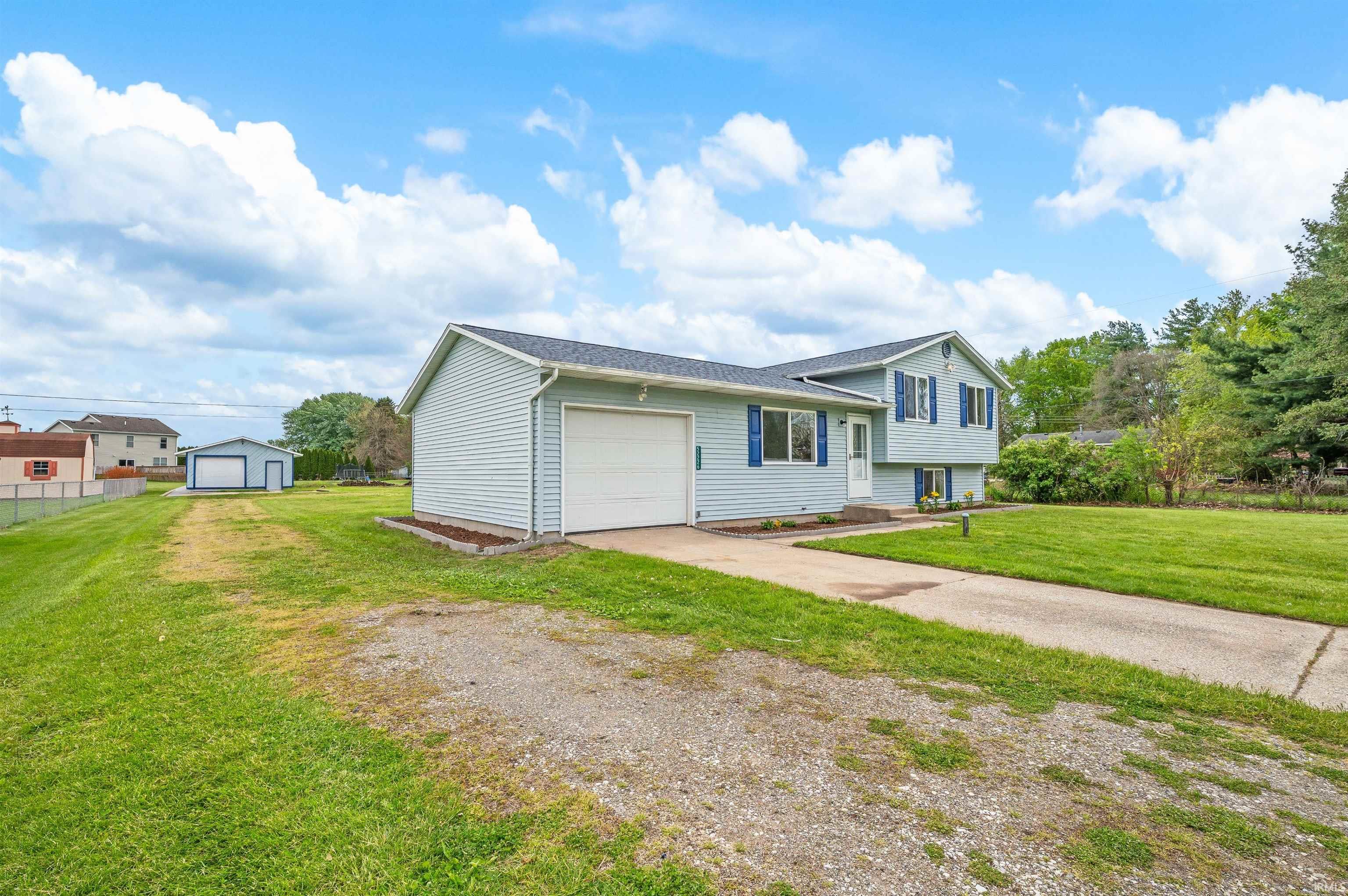 Light blue siding residence with an attached garage, featuring a concrete driveway and an expansive grassy lawn