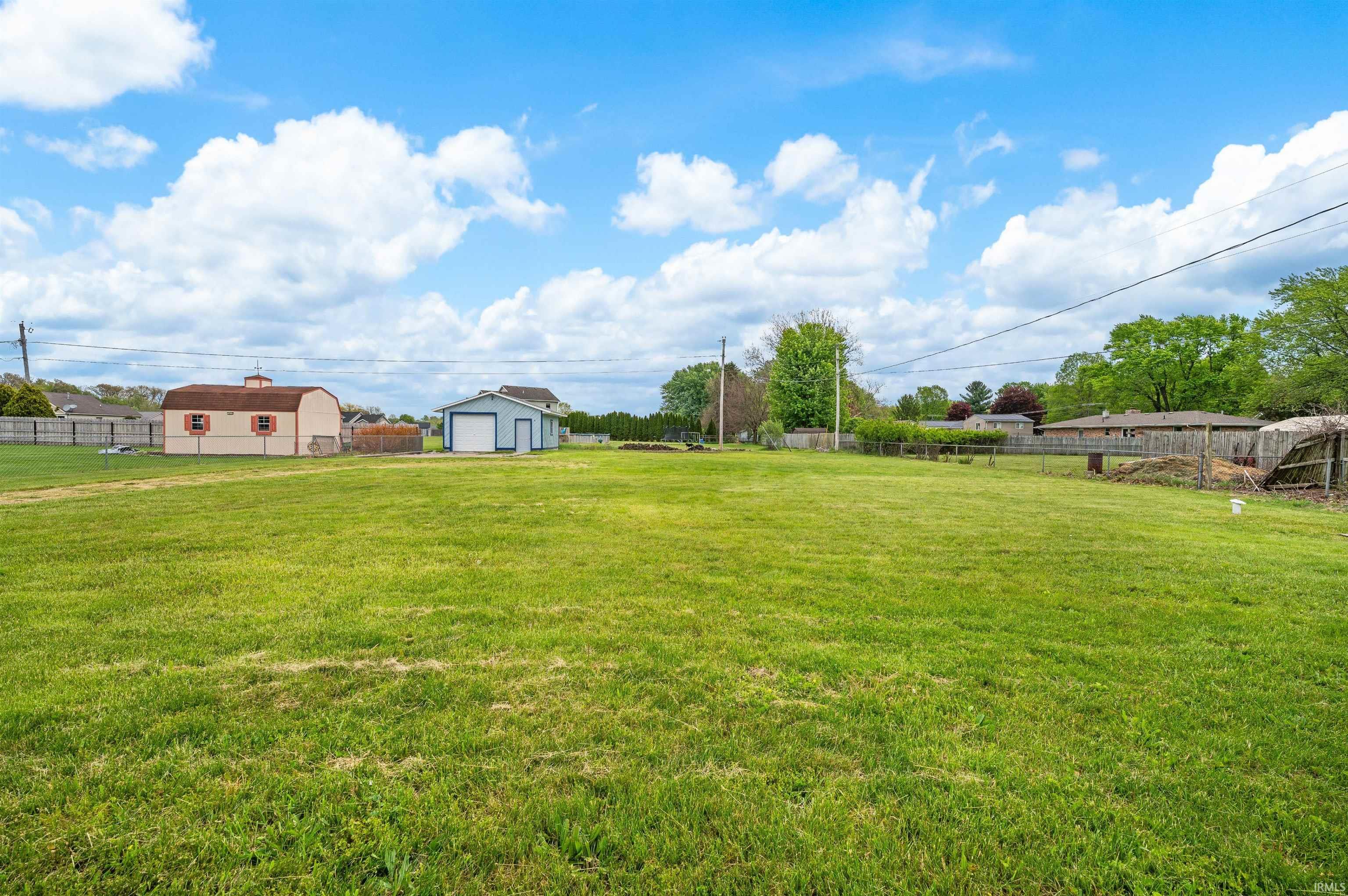 Expansive green lawn featuring two outbuildings and perimeter fencing