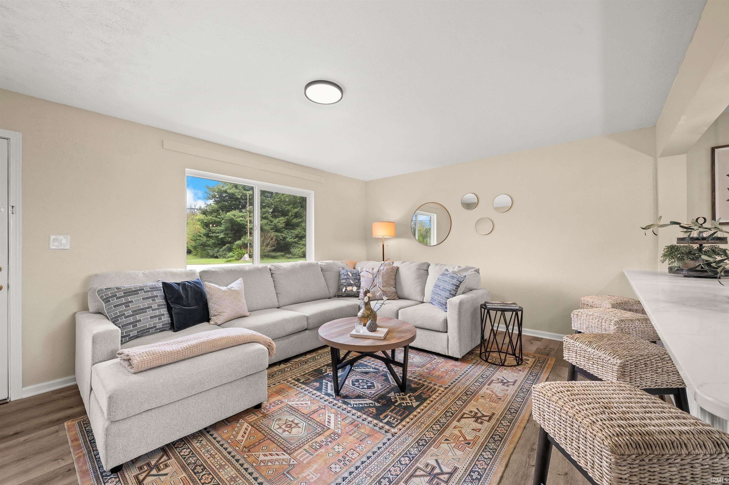Living area with light-toned walls, wood-finish flooring, and a large picture window
