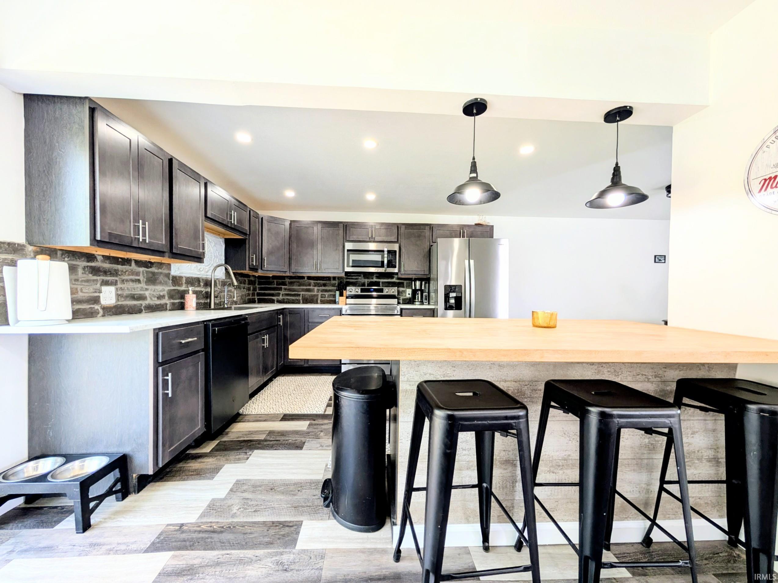 Kitchen featuring dark grey cabinetry, light countertops, and a stone-look backsplash
