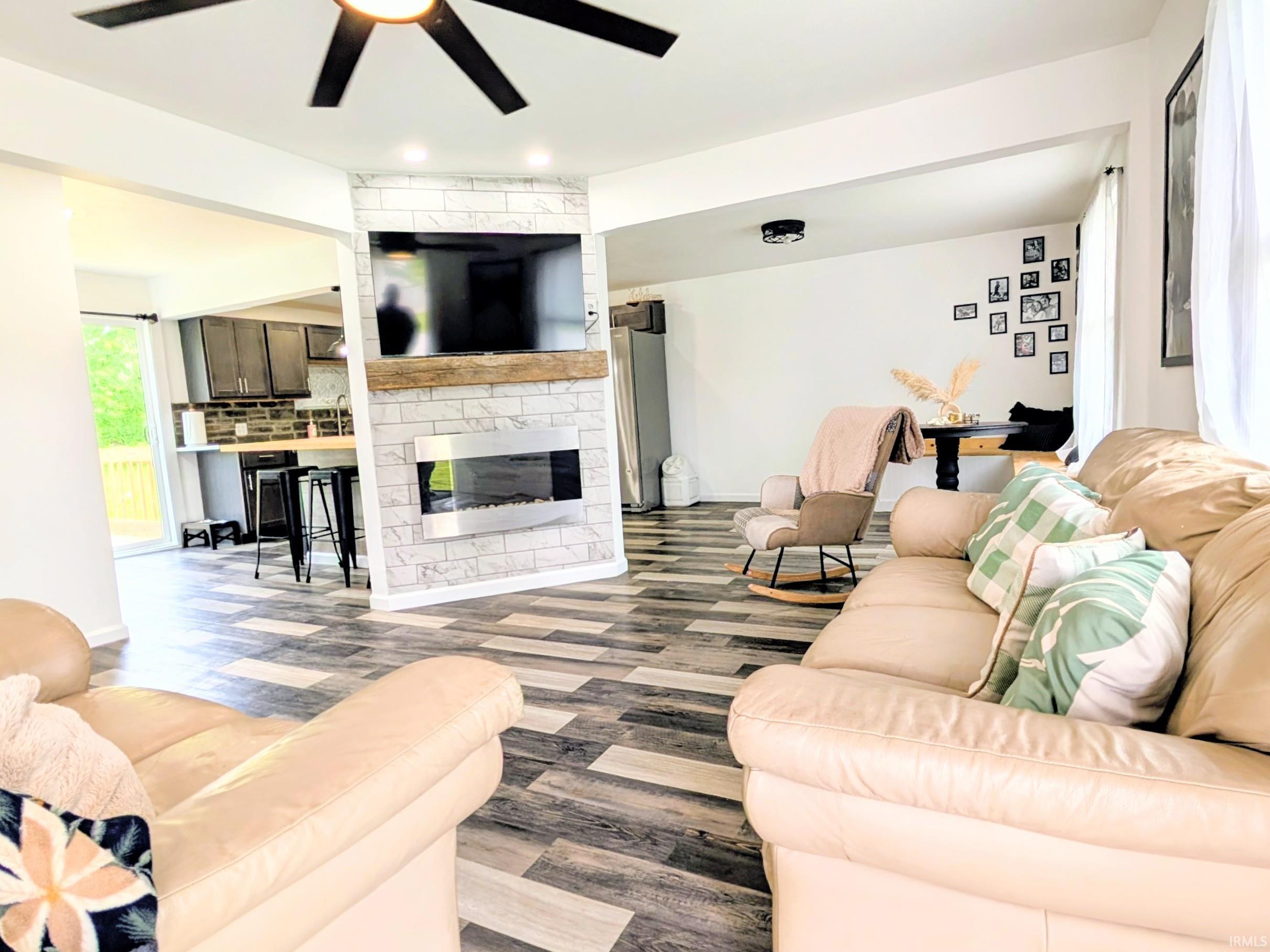 Living area featuring wood-finish flooring and a ceiling fan with integrated lighting
