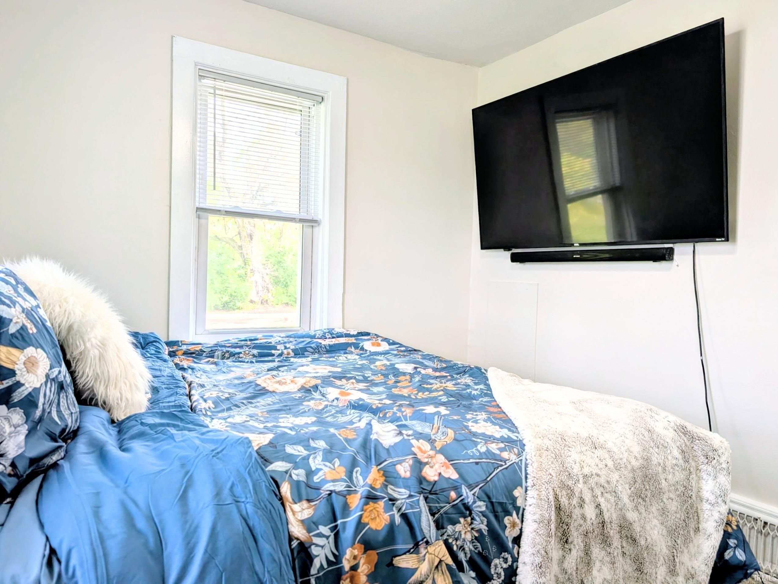 Bright room featuring a single window with blinds, light wall paint, and white trim