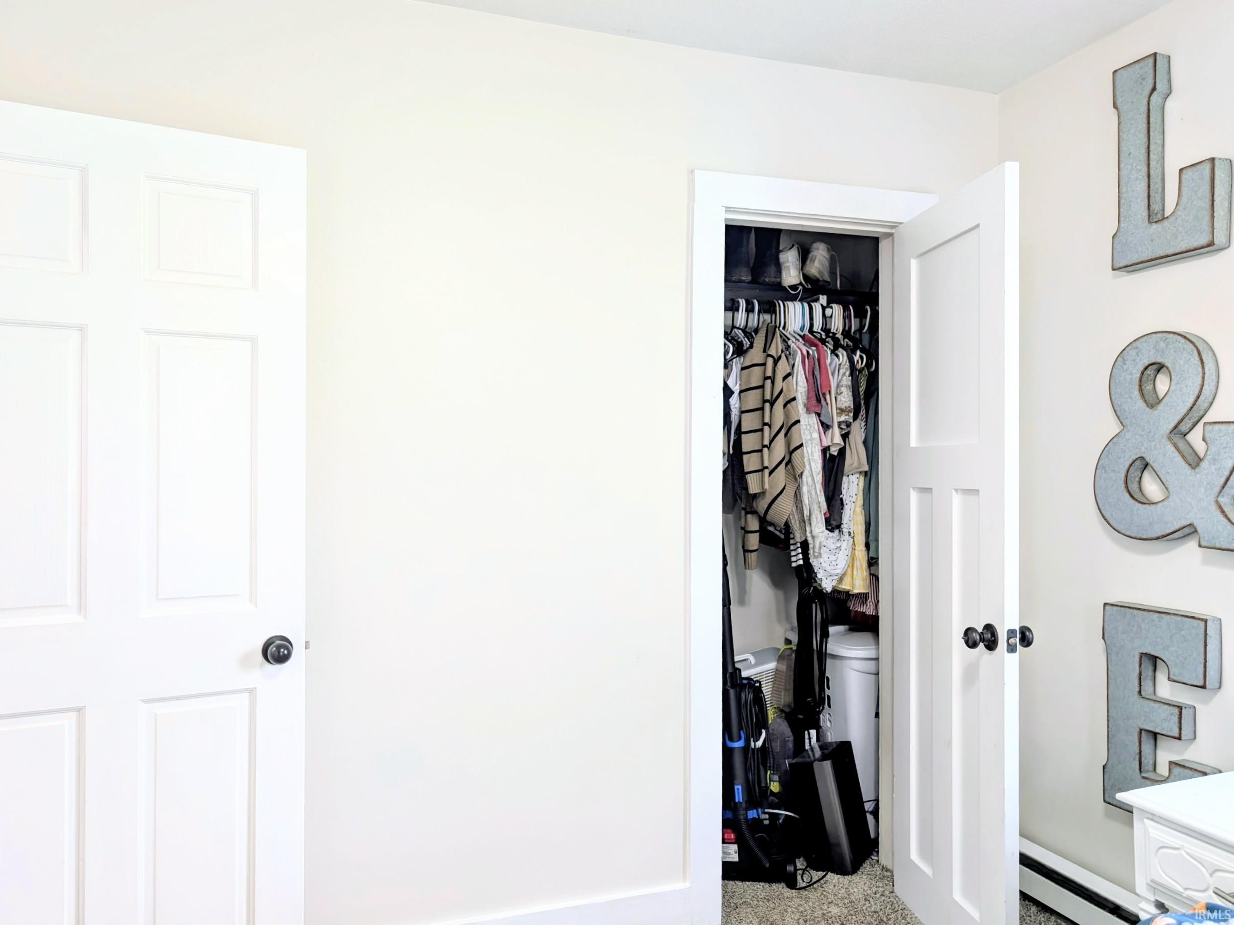 Bright interior space featuring a white six-panel door with a black doorknob and a closet with an open white door