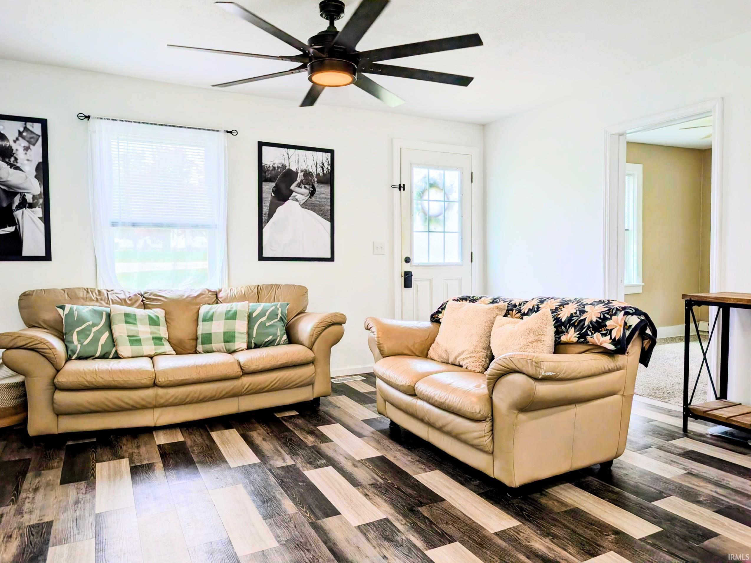 Spacious interior featuring wood-finish flooring, a contemporary ceiling fan, and a transom window above the entry door