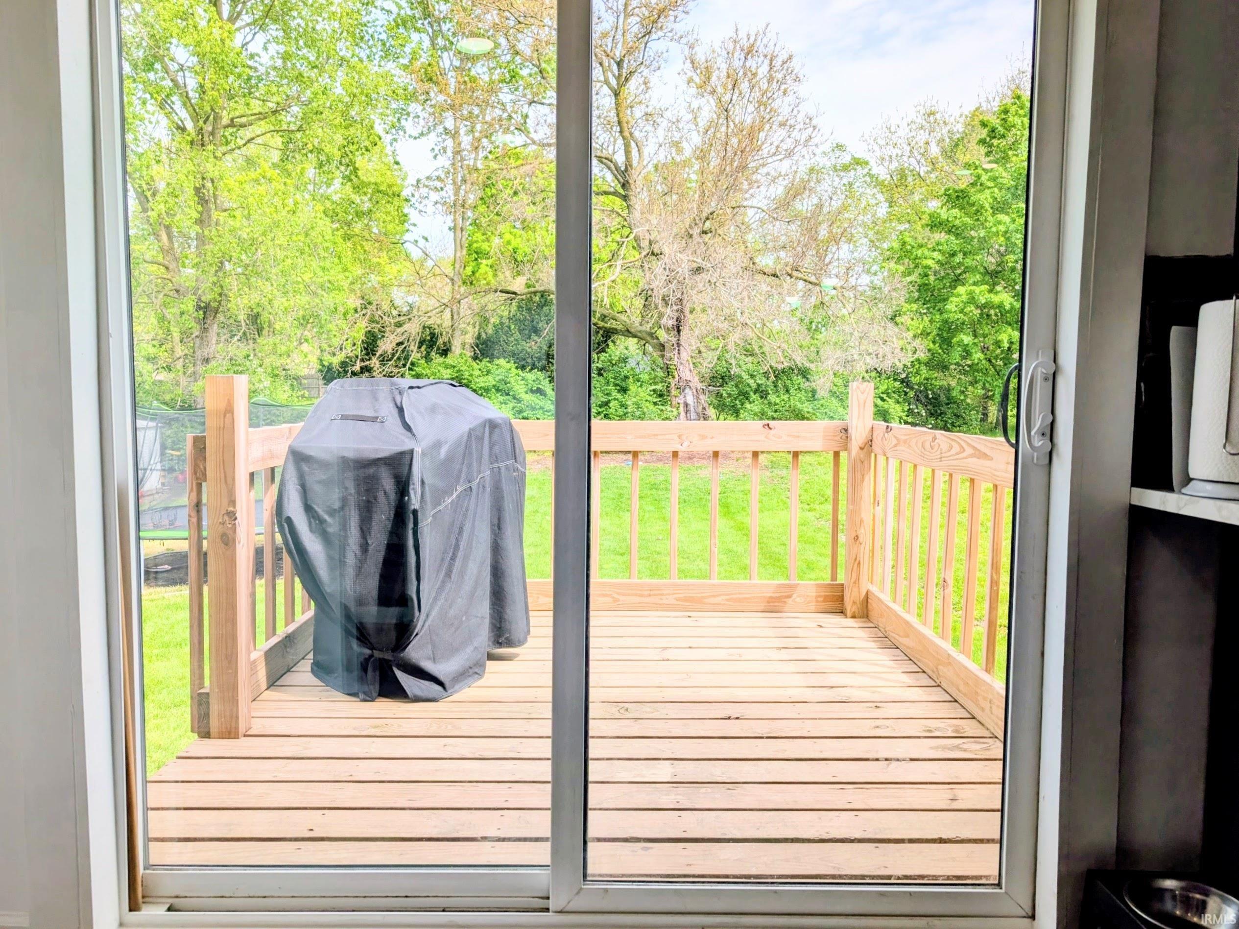Outdoor wooden deck with a complete wooden railing system, framed by a sliding glass patio door