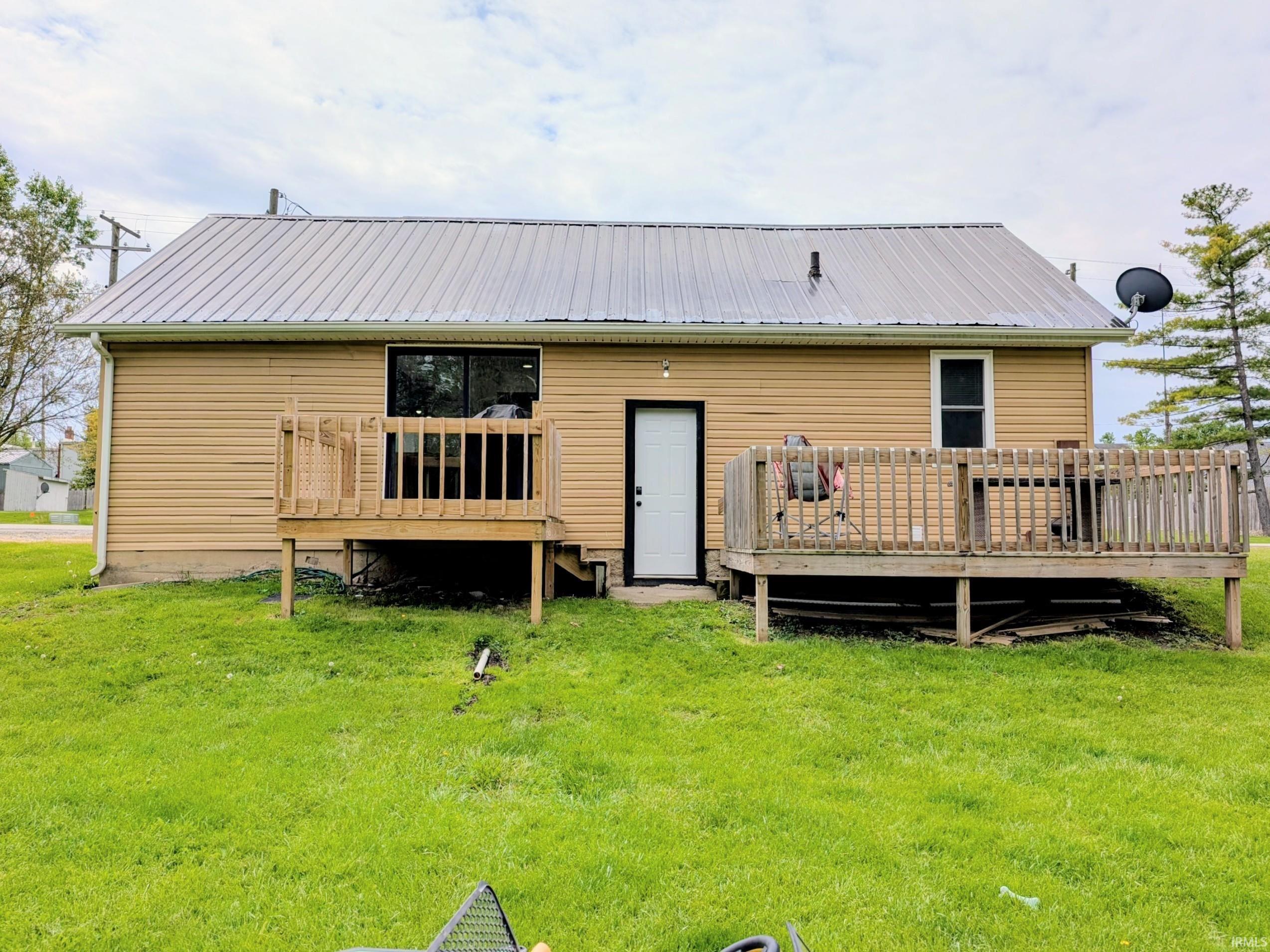 Rear exterior with two elevated wooden decks, tan vinyl siding, and a silver-colored metal roof