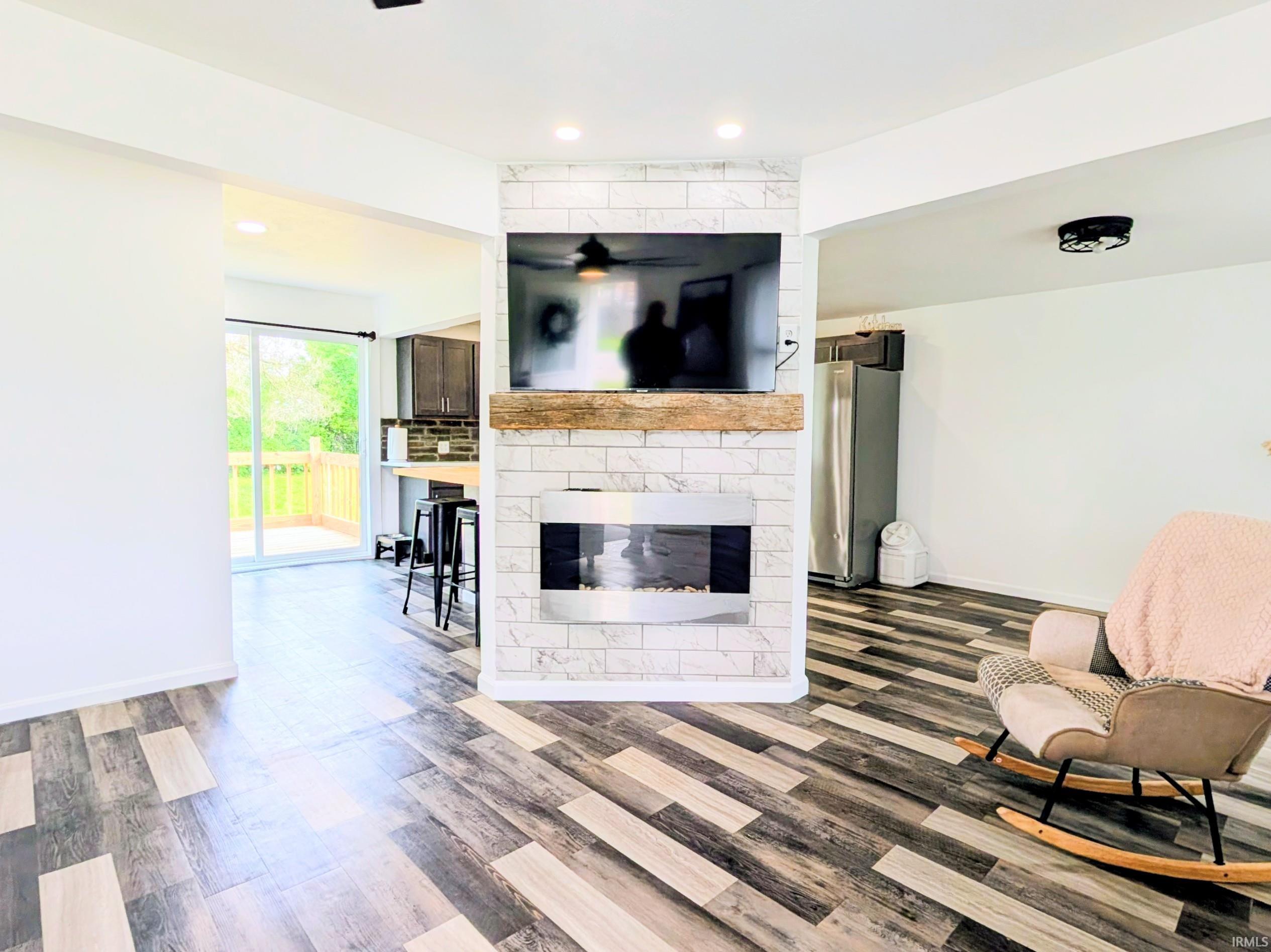 Wood-finish flooring throughout, featuring a modern fireplace with a white subway tile surround and a wood mantel