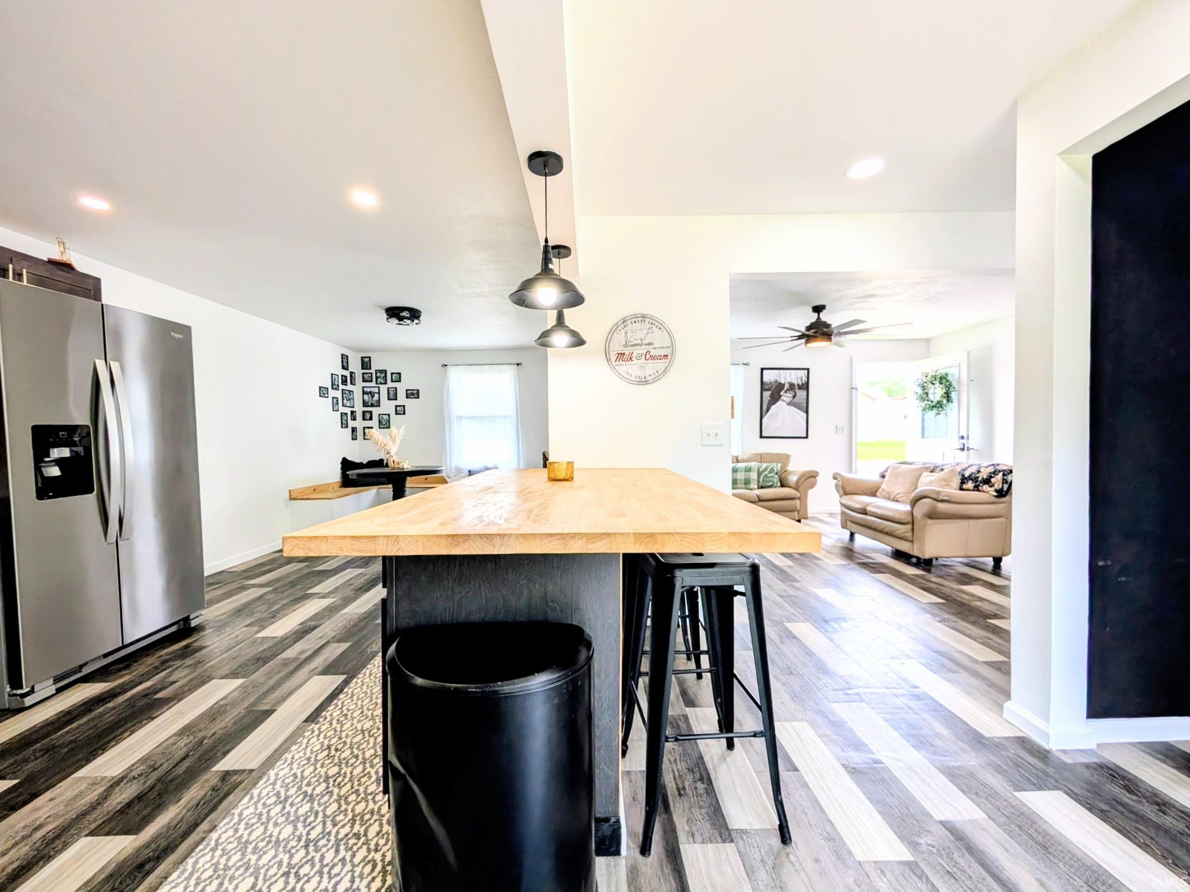 Open-concept kitchen and living area featuring wood-finish flooring, recessed lighting, and a kitchen island with pendant lighting