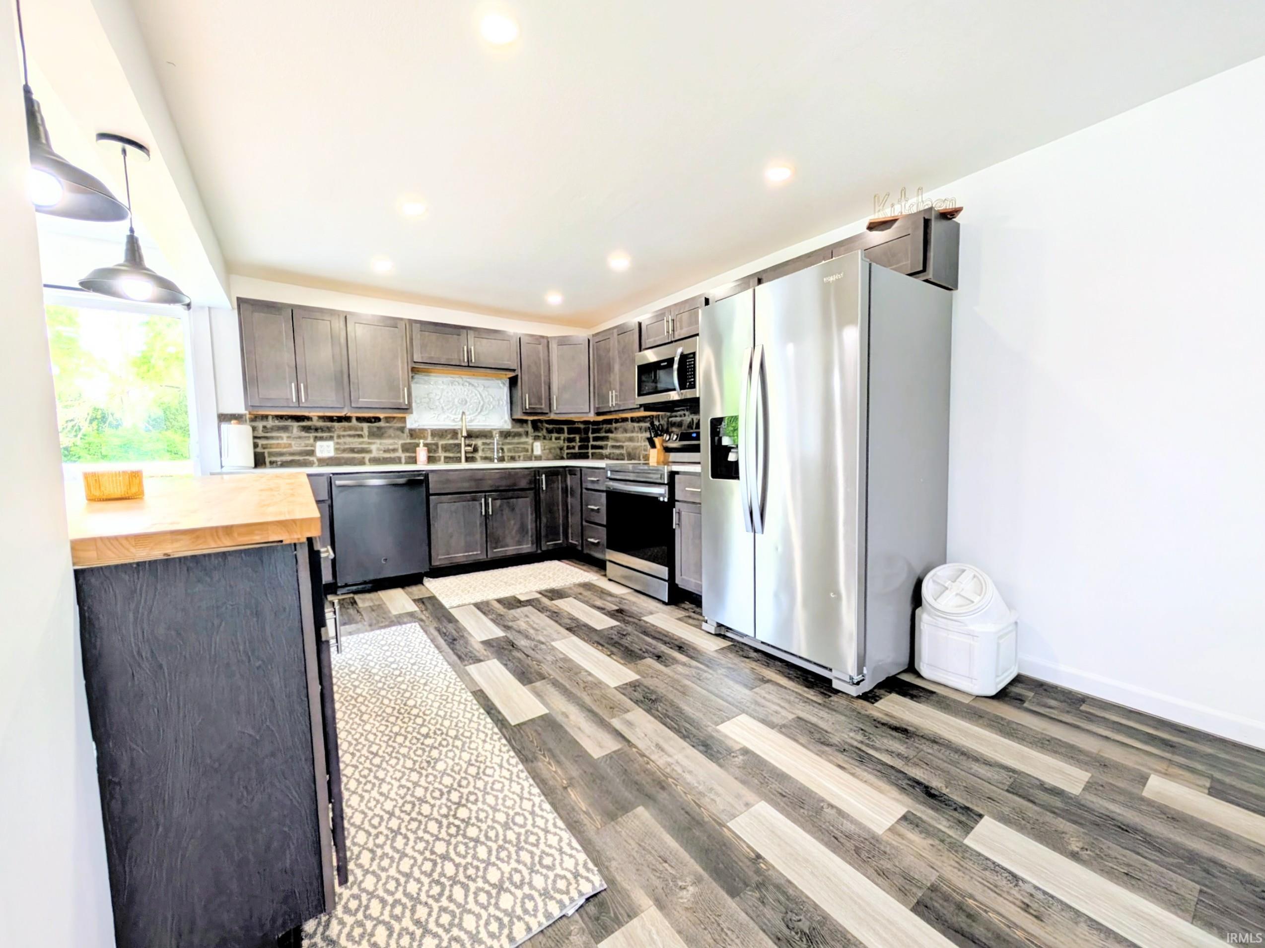 Kitchen featuring dark wood-finish cabinetry, stainless steel appliances, and a mosaic tile backsplash