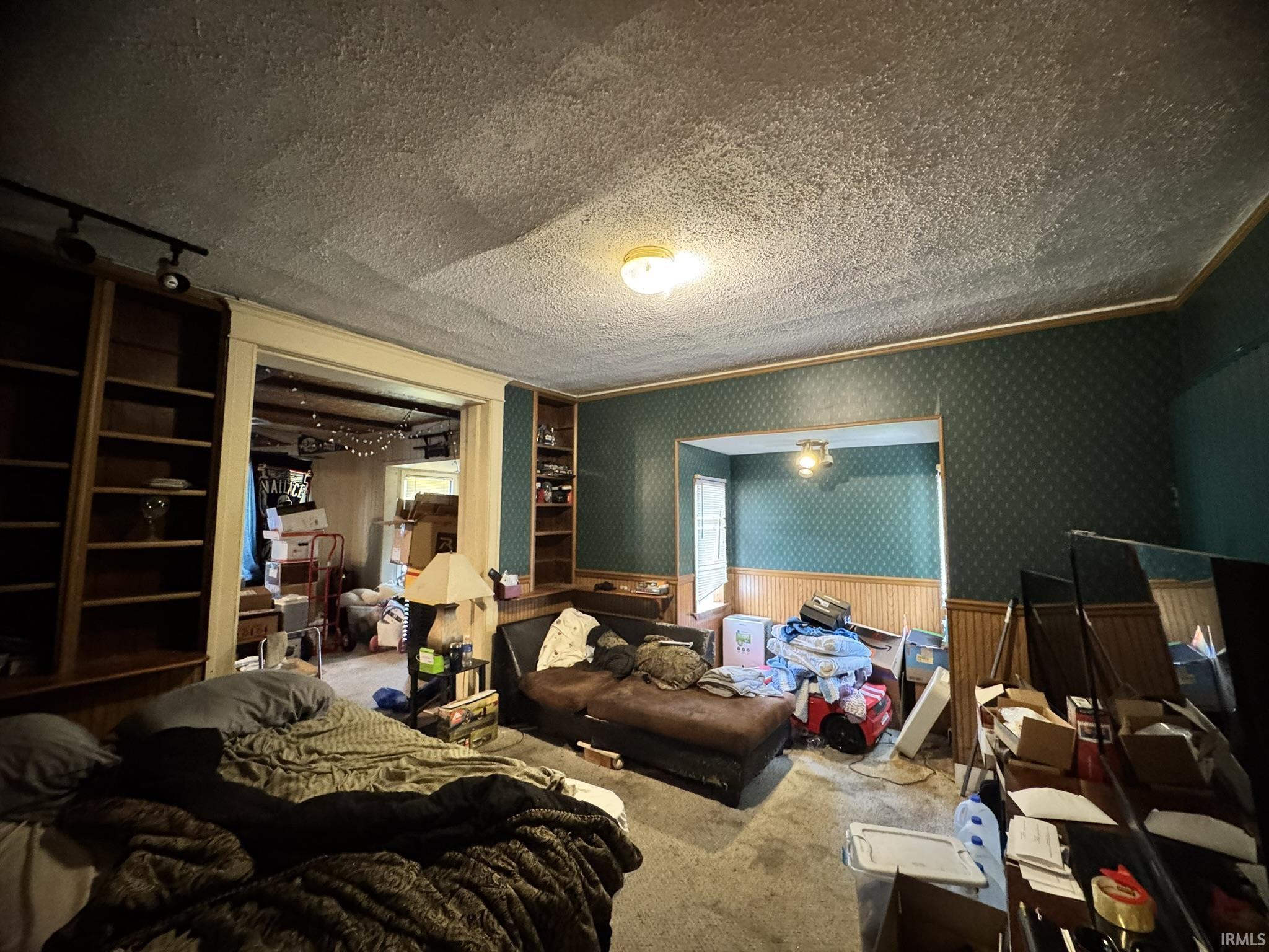 Room featuring patterned wallpaper, wainscoting, and built-in shelving