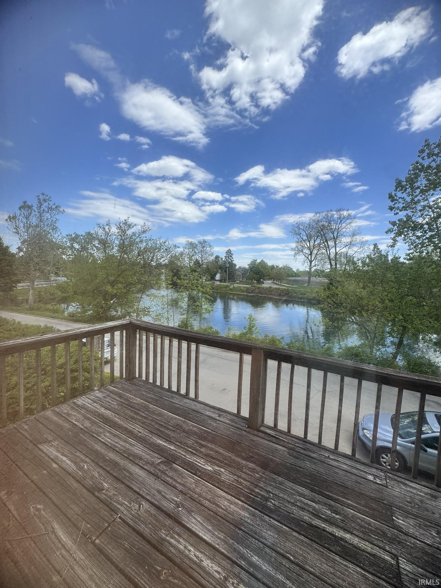 Expansive outdoor deck with wood railing, offering water scenery