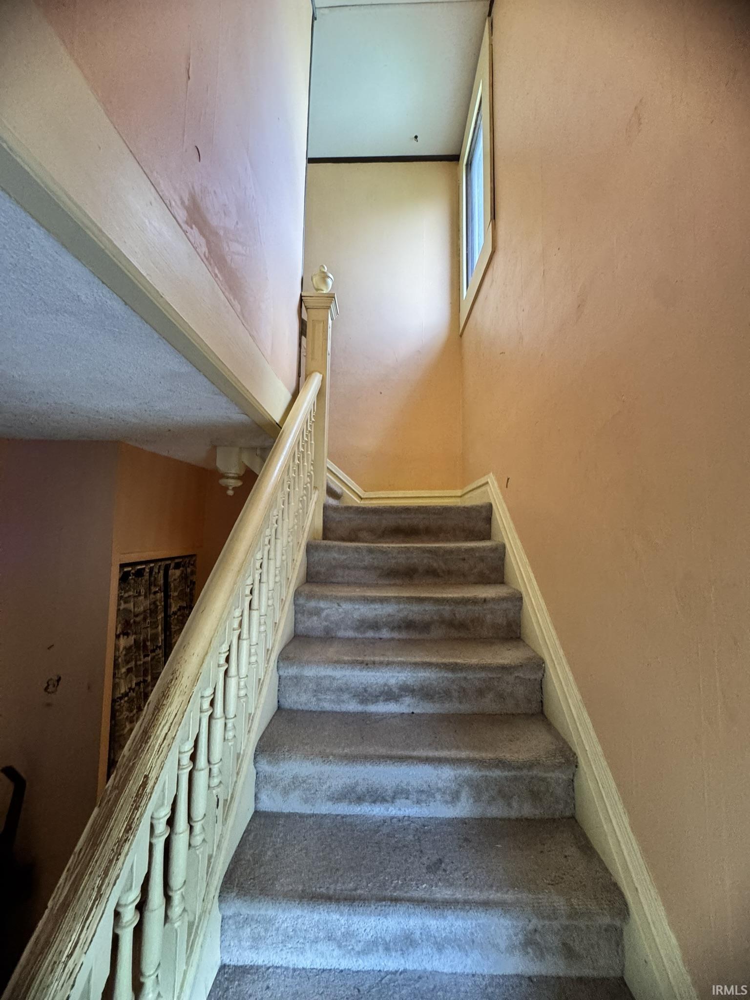 Carpeted staircase with an ornate wood-finish banister