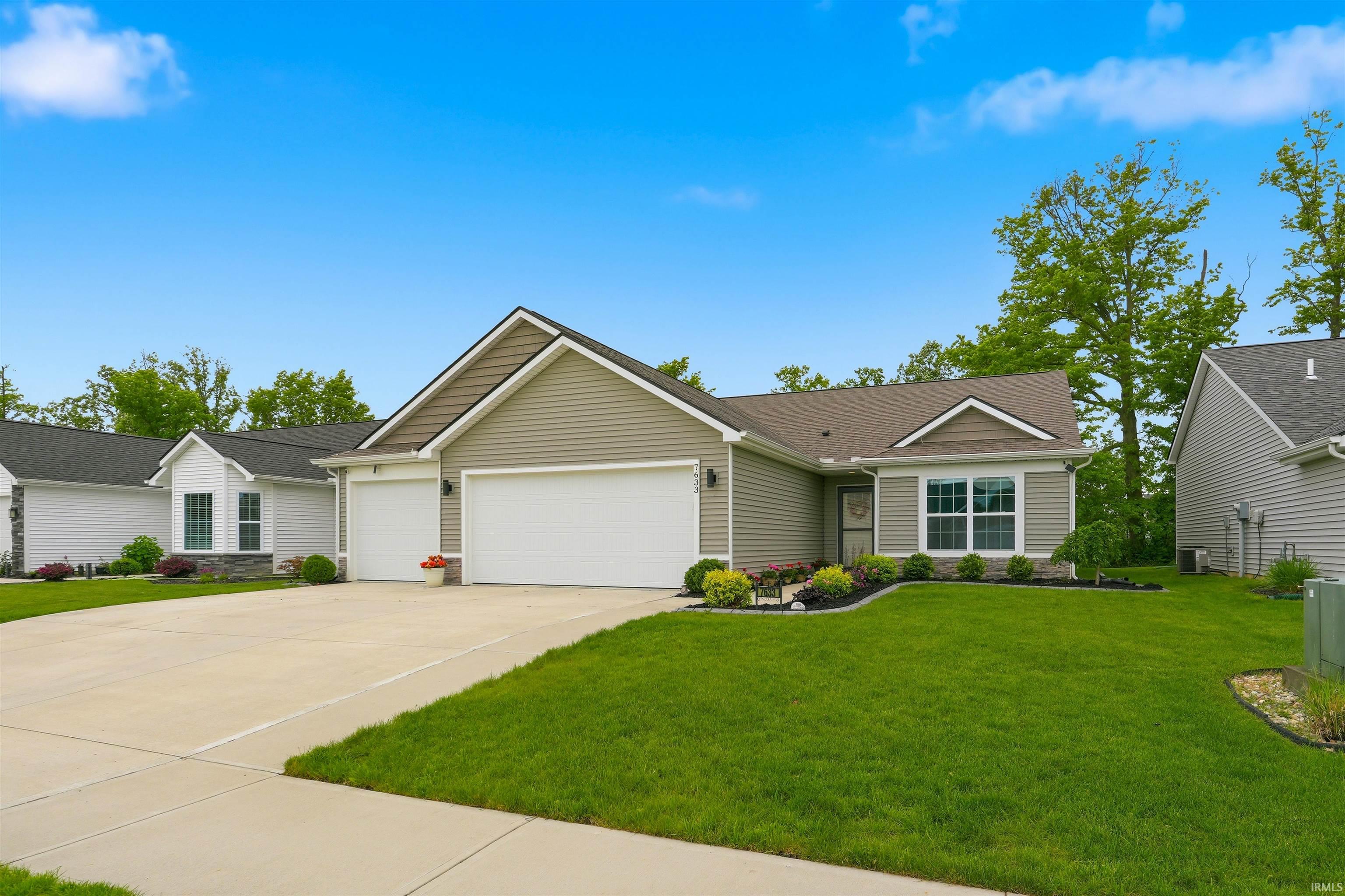 Contemporary ranch-style home featuring a two-car garage, light-colored siding, and a dark shingle roof