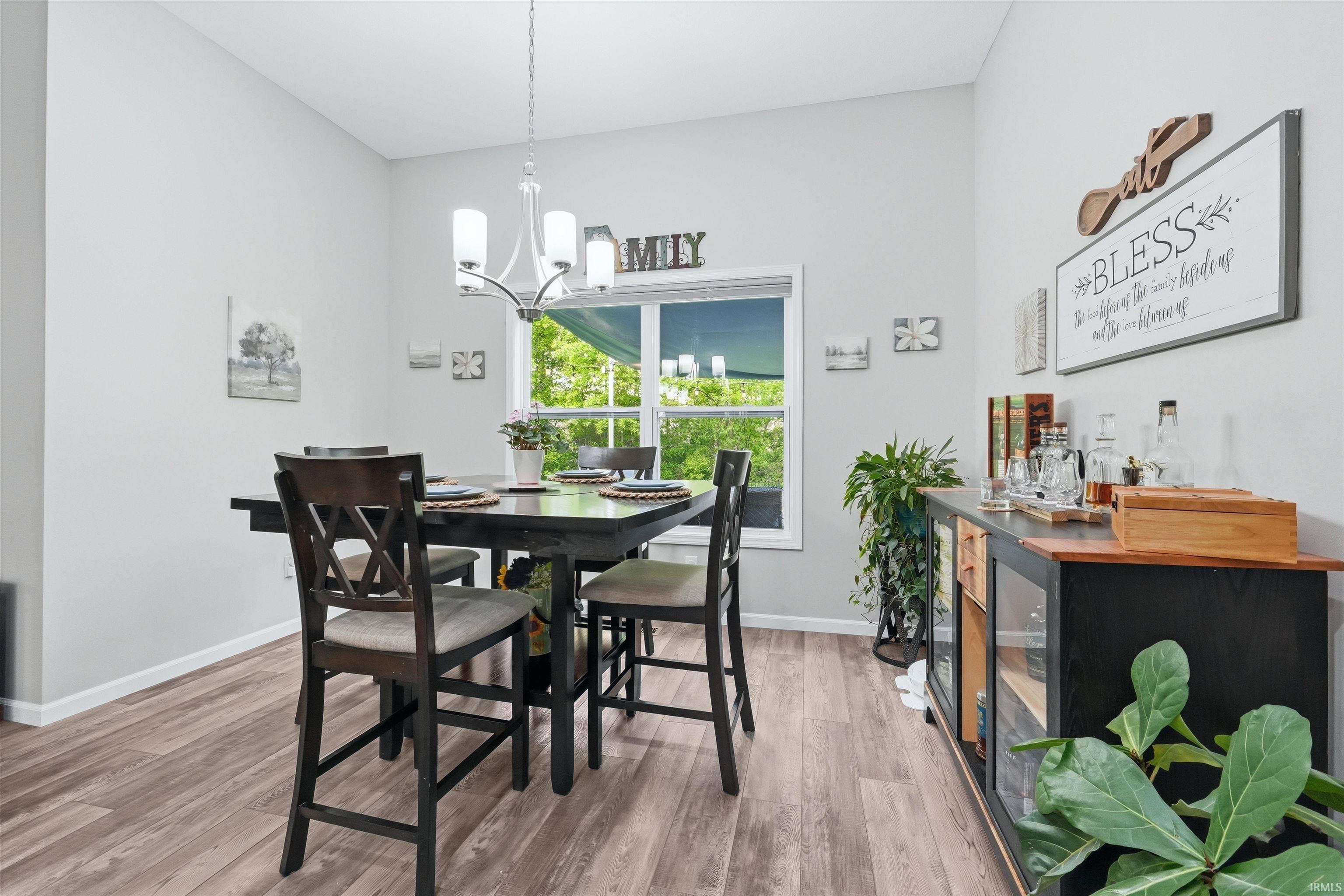Dining area featuring wood-finish flooring, a white trim window, a contemporary ceiling light fixture, and a built-in sideboard with a wood-finish top