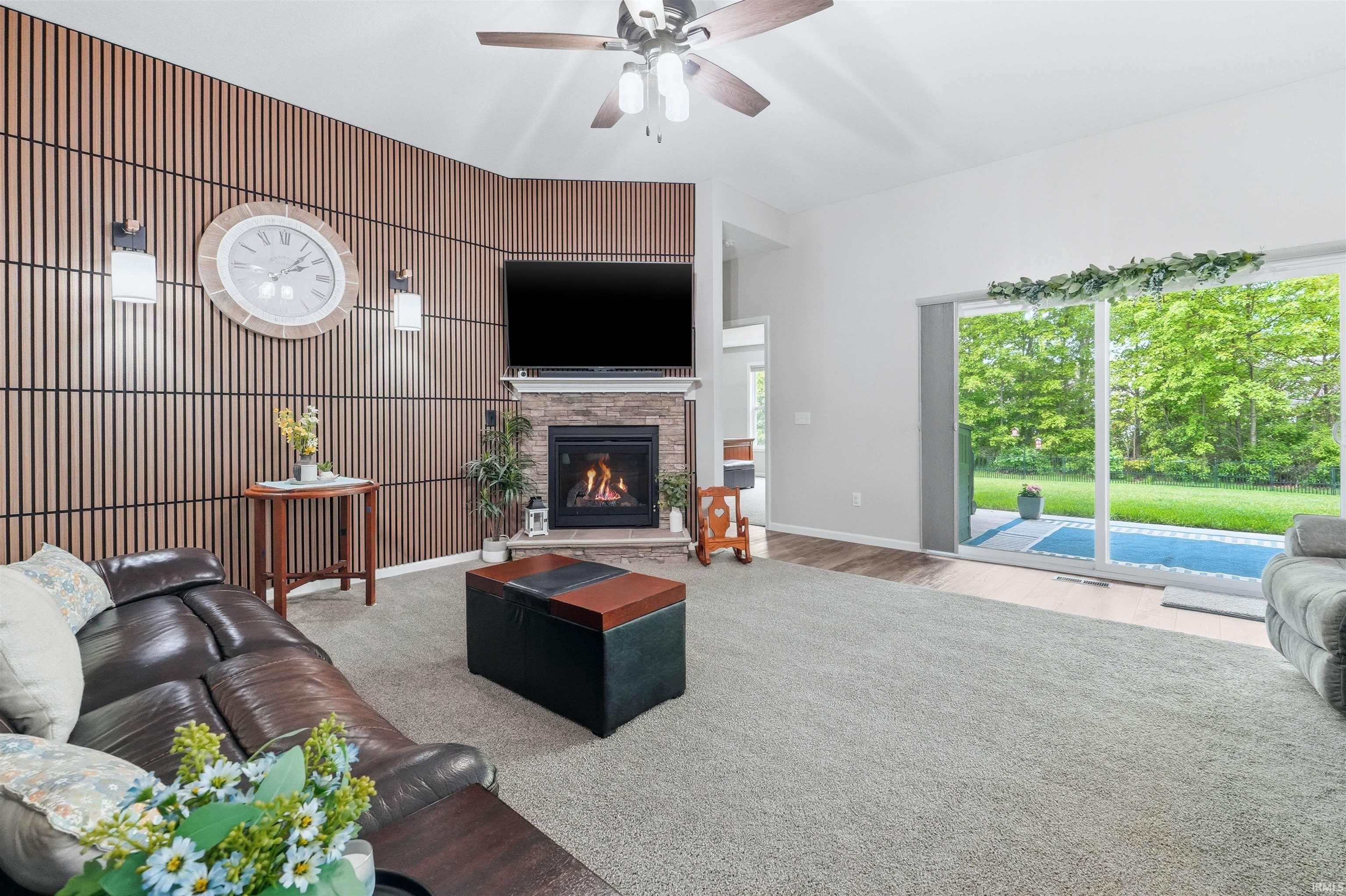 Living area featuring a stone-surround fireplace, slatted wood-finish accent wall, and vaulted ceilings
