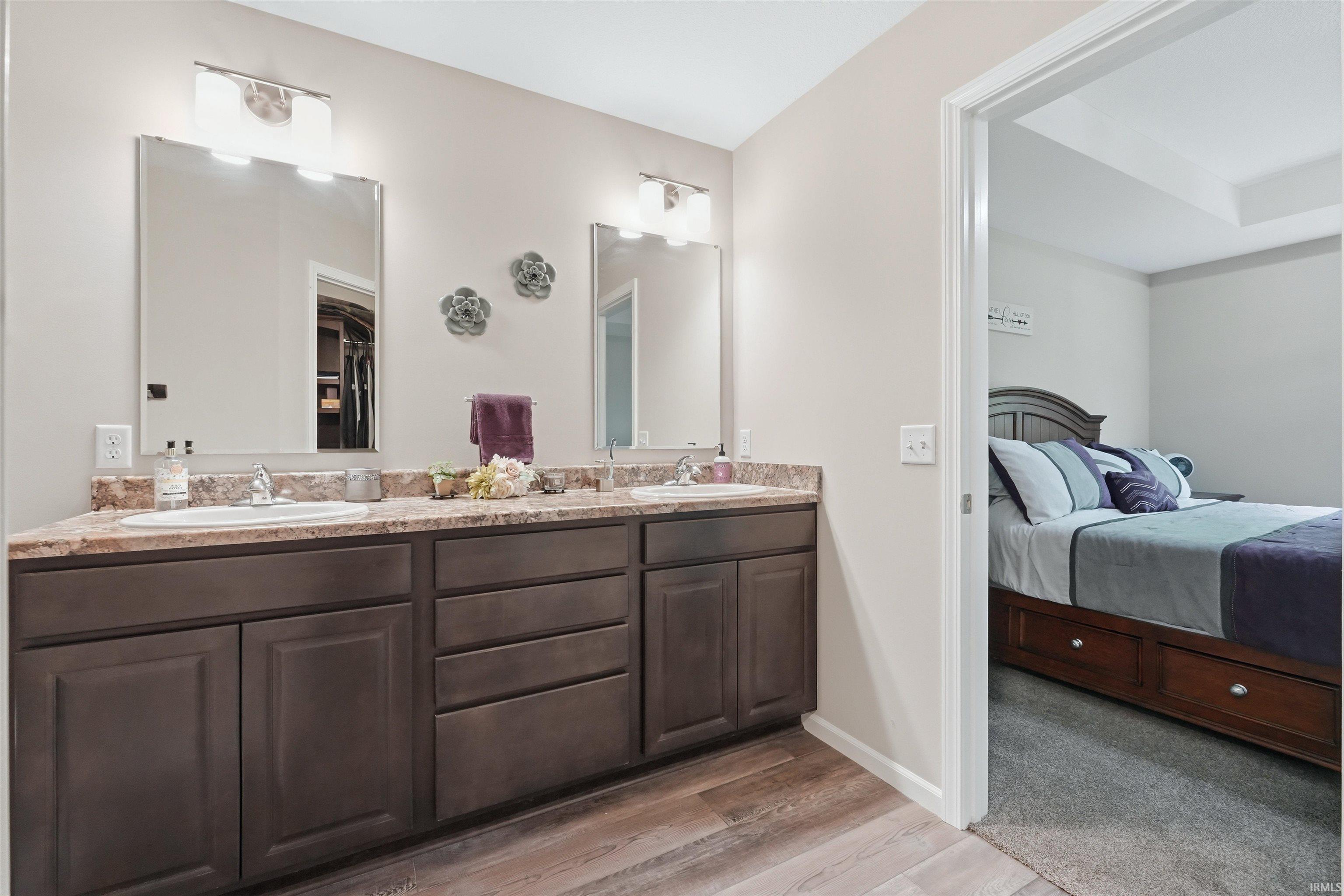 Dual vanity with brown cabinetry, light-toned countertop, and undermount sinks