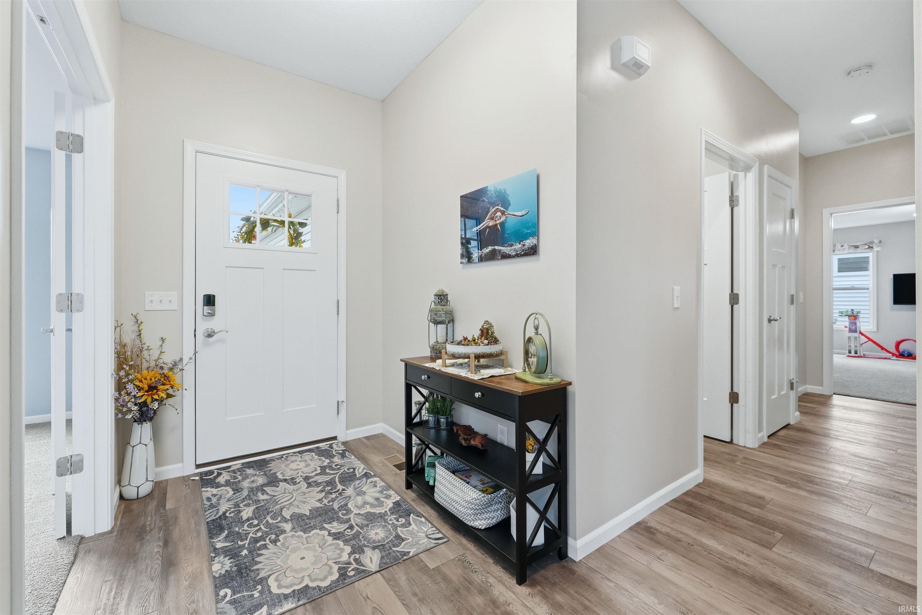 Inviting entryway featuring a white paneled door with glass inserts, wood-finish flooring, and light neutral wall tones