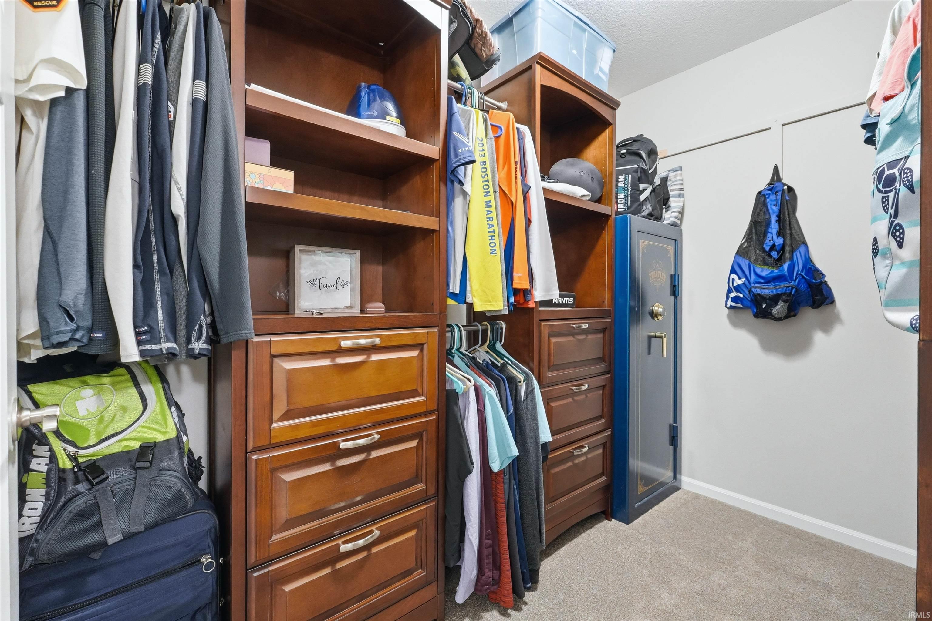 Custom closet organization system featuring wood-finish cabinetry, open shelving, and integrated drawers