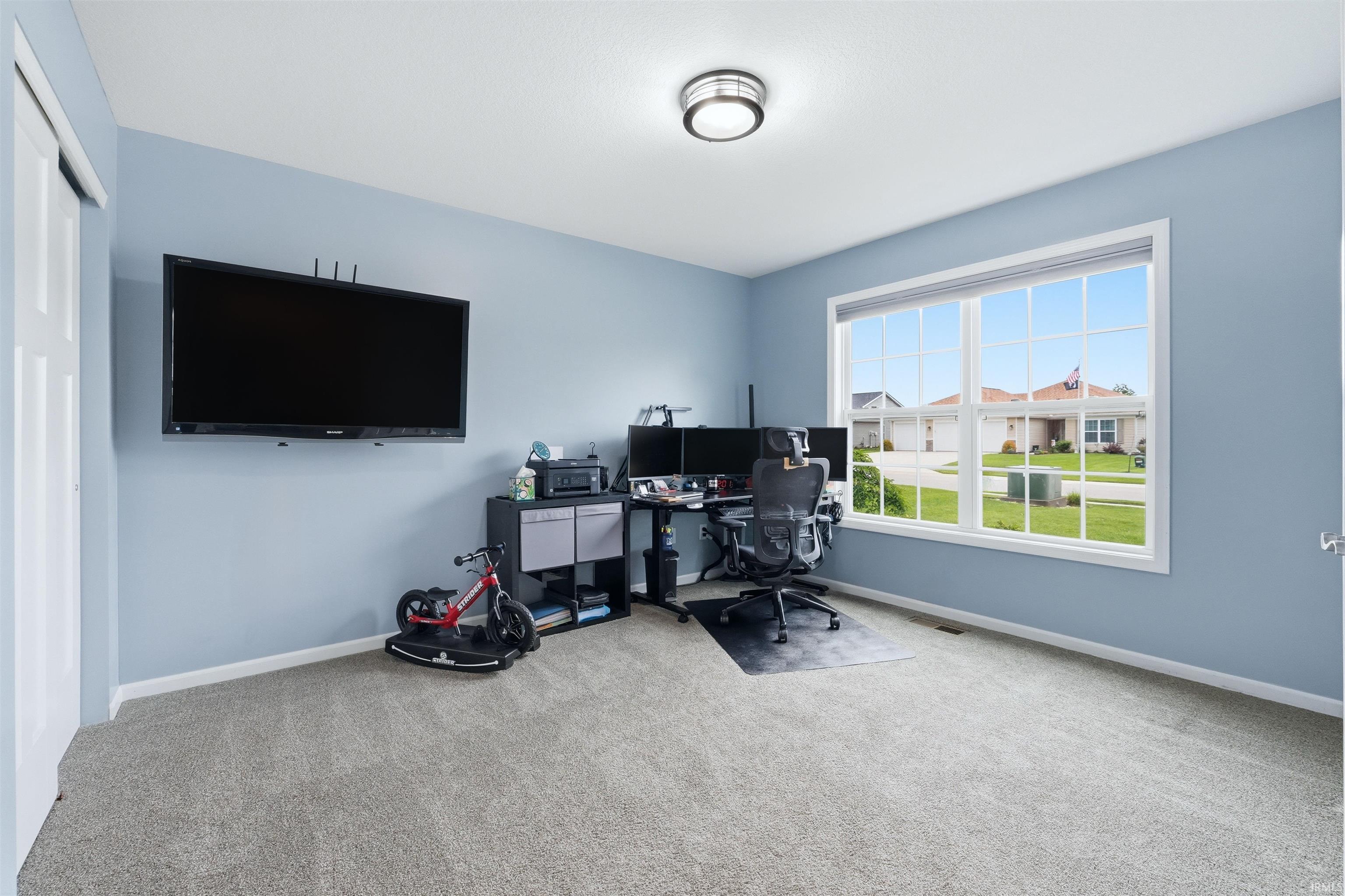 Room featuring a large window, soft blue wall paint, and gray carpet