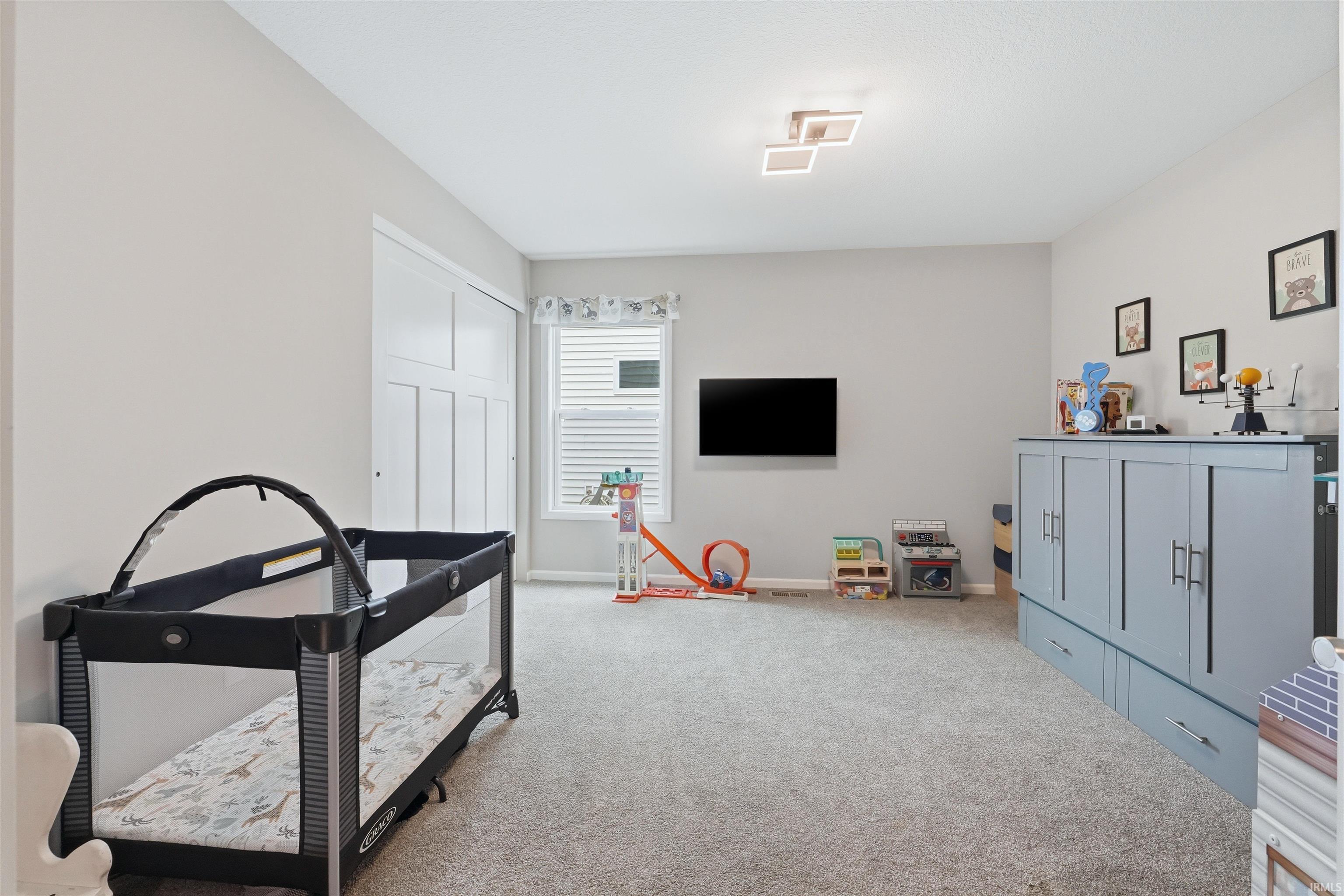 Spacious room featuring light gray wall paint, carpeting, a window with horizontal blinds, and a built-in closet with bifold doors