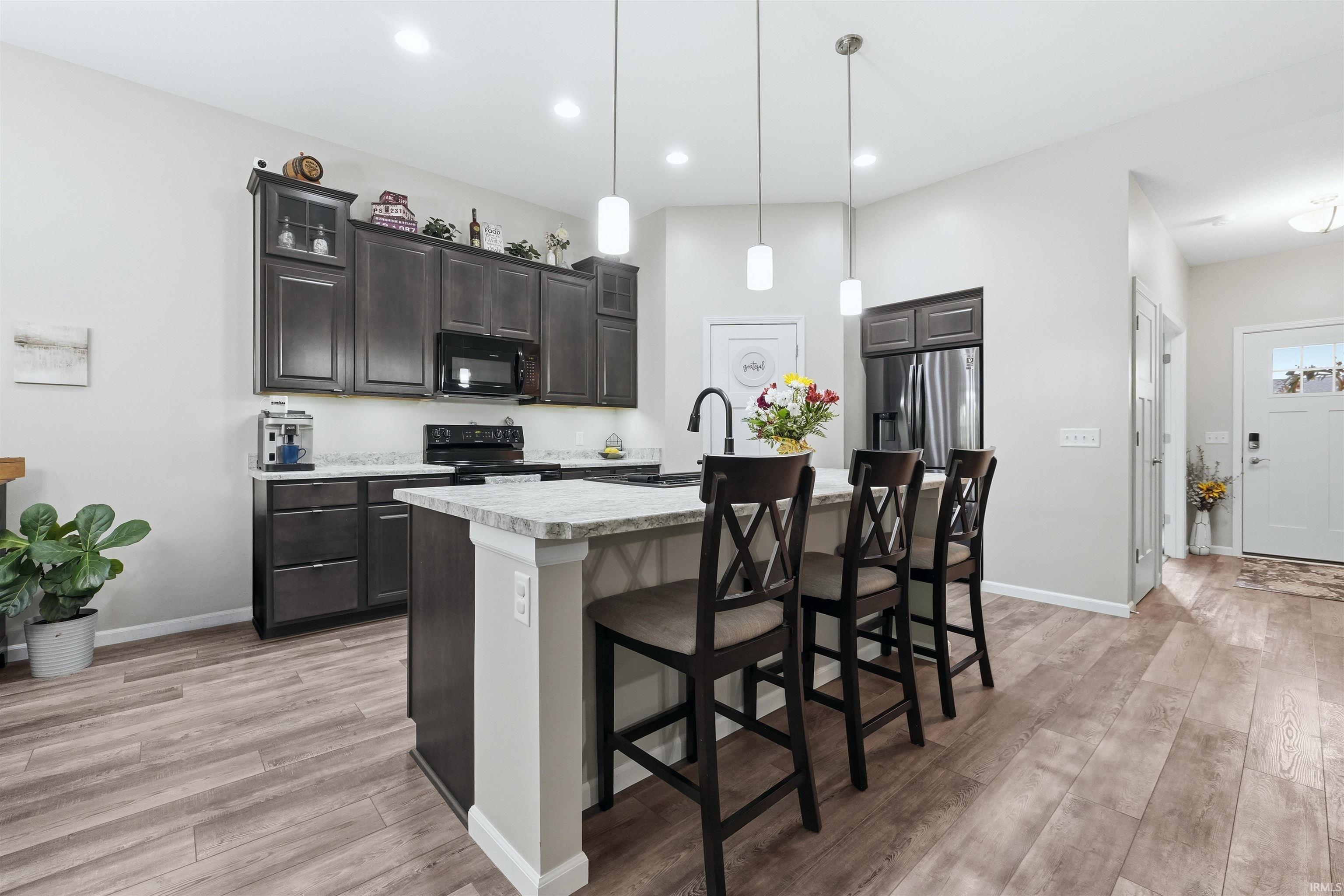 Modern kitchen featuring dark-stained cabinetry, light-toned countertops, and wood-finish flooring