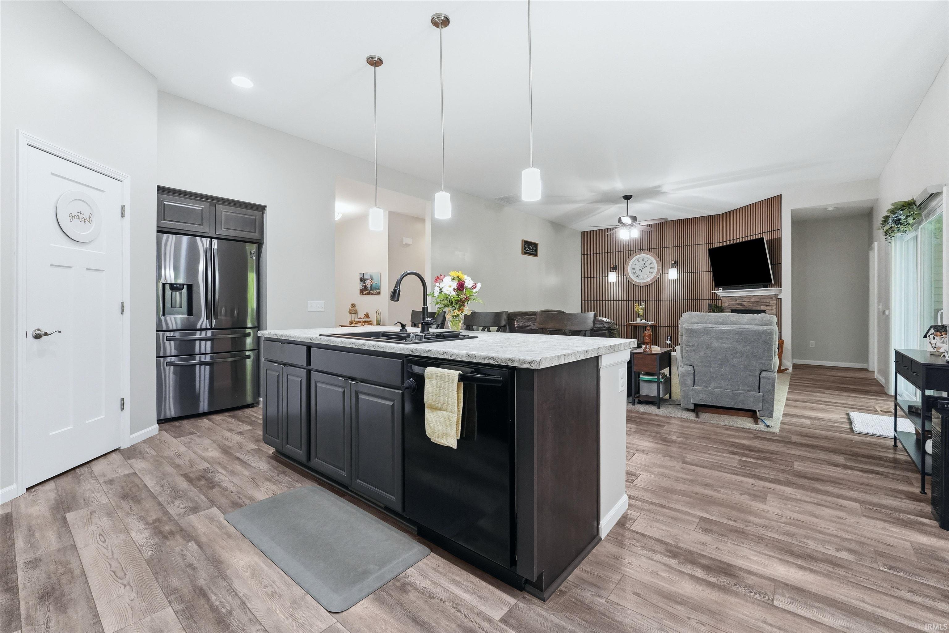 Kitchen featuring an island with a built-in sink, dark cabinetry, and a light-toned countertop