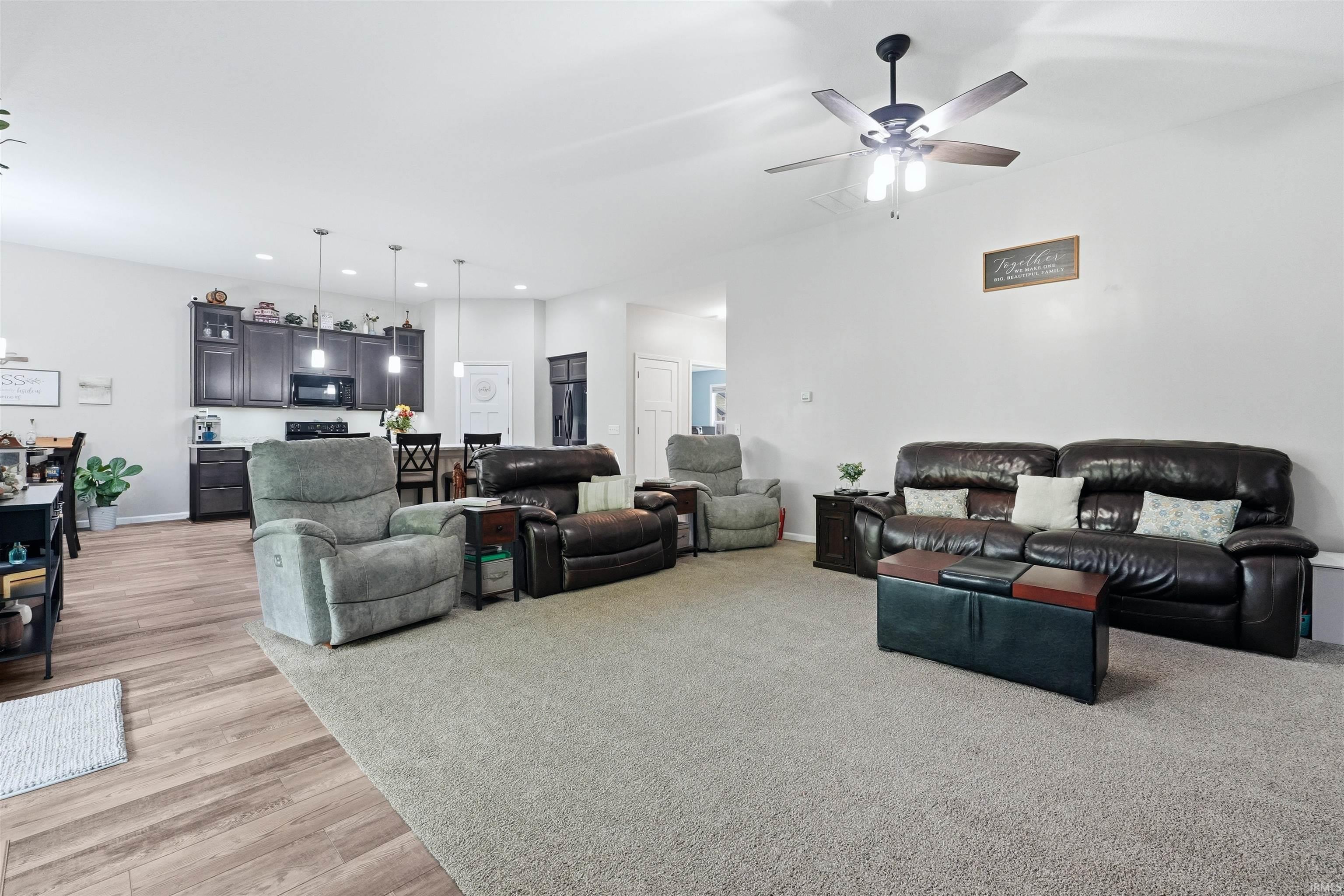 Open-concept living area featuring a ceiling fan, light-colored walls, wood-finish flooring, and recessed lighting
