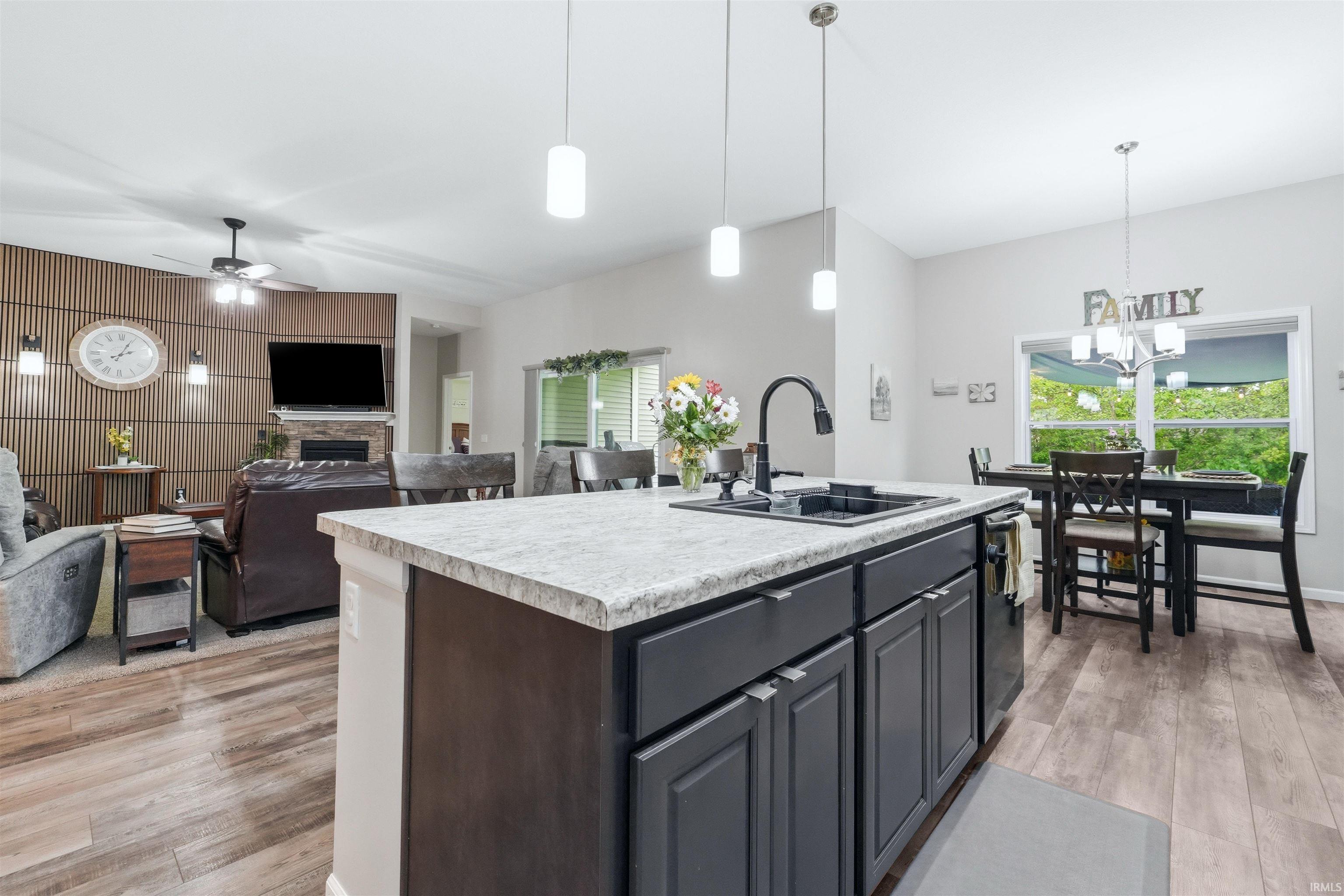Kitchen island with granite-style countertop, integrated sink, and black cabinetry