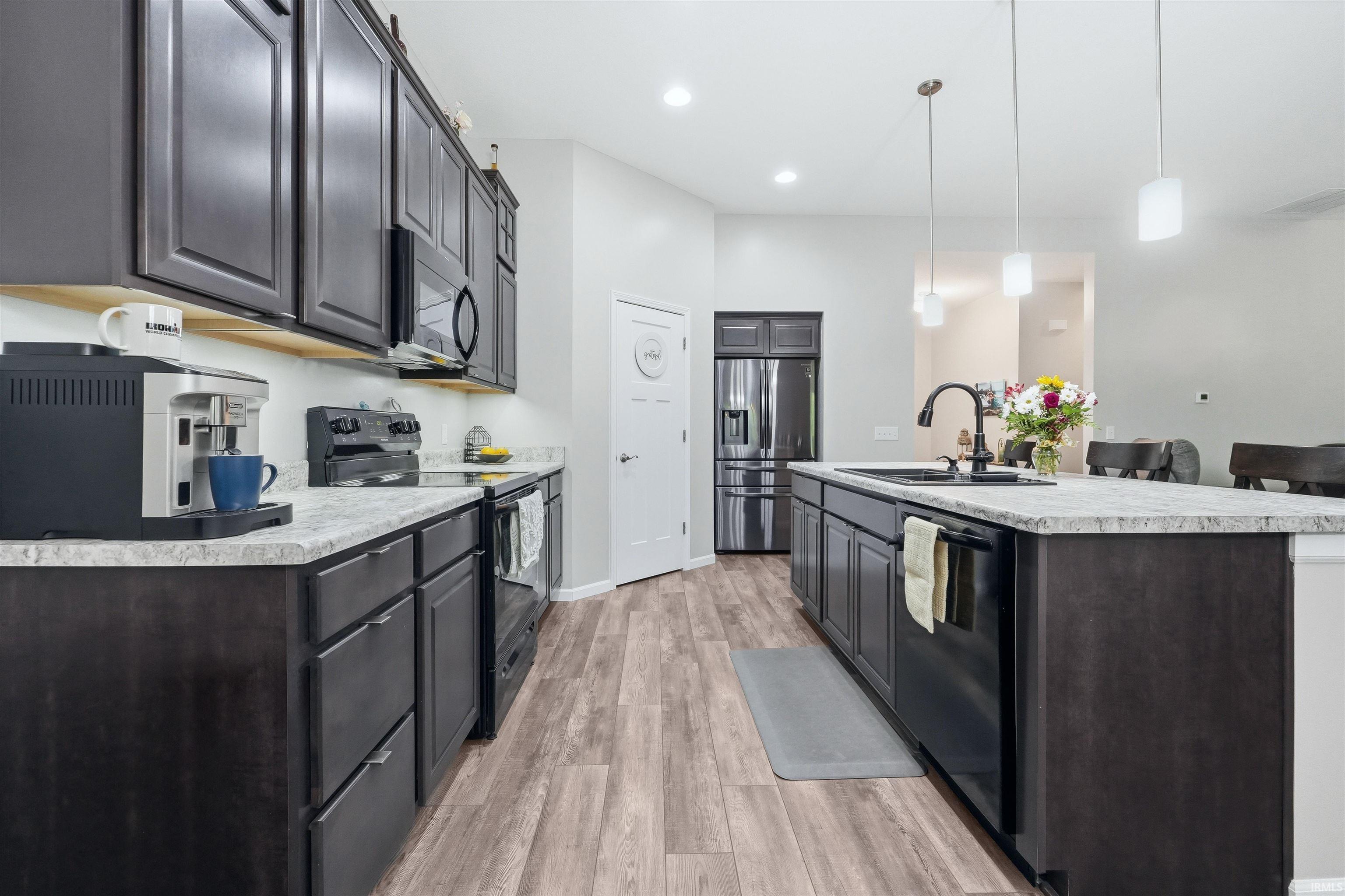 Modern kitchen featuring dark wood cabinetry, light-toned countertops, and wood-finish flooring