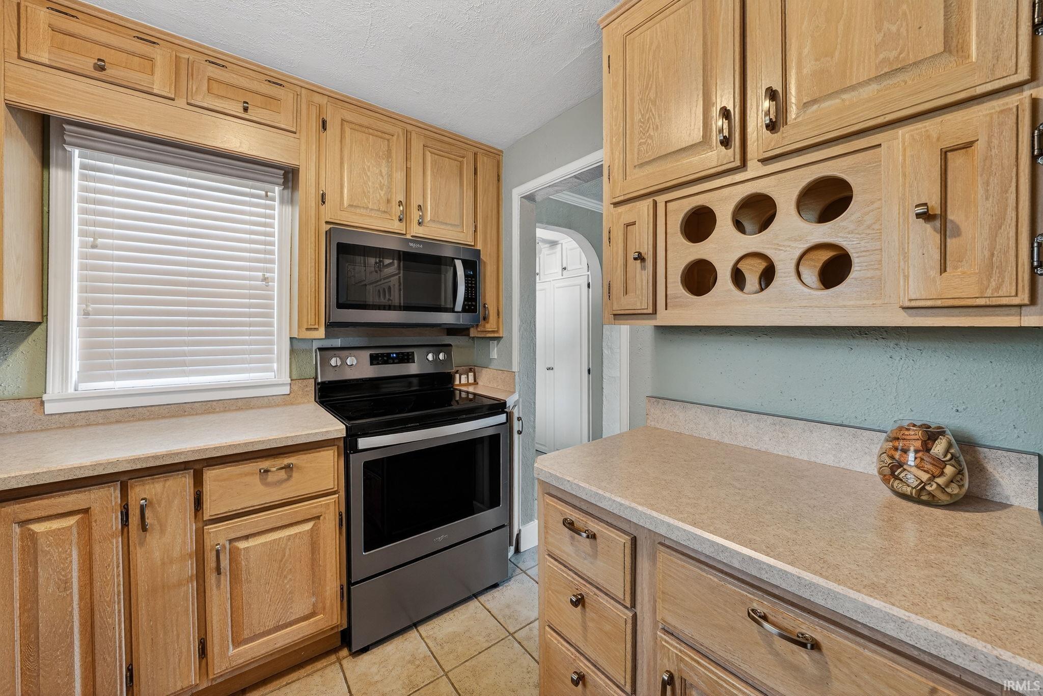 Kitchen featuring light wood cabinetry with brushed nickel hardware, laminate countertops, and tile flooring