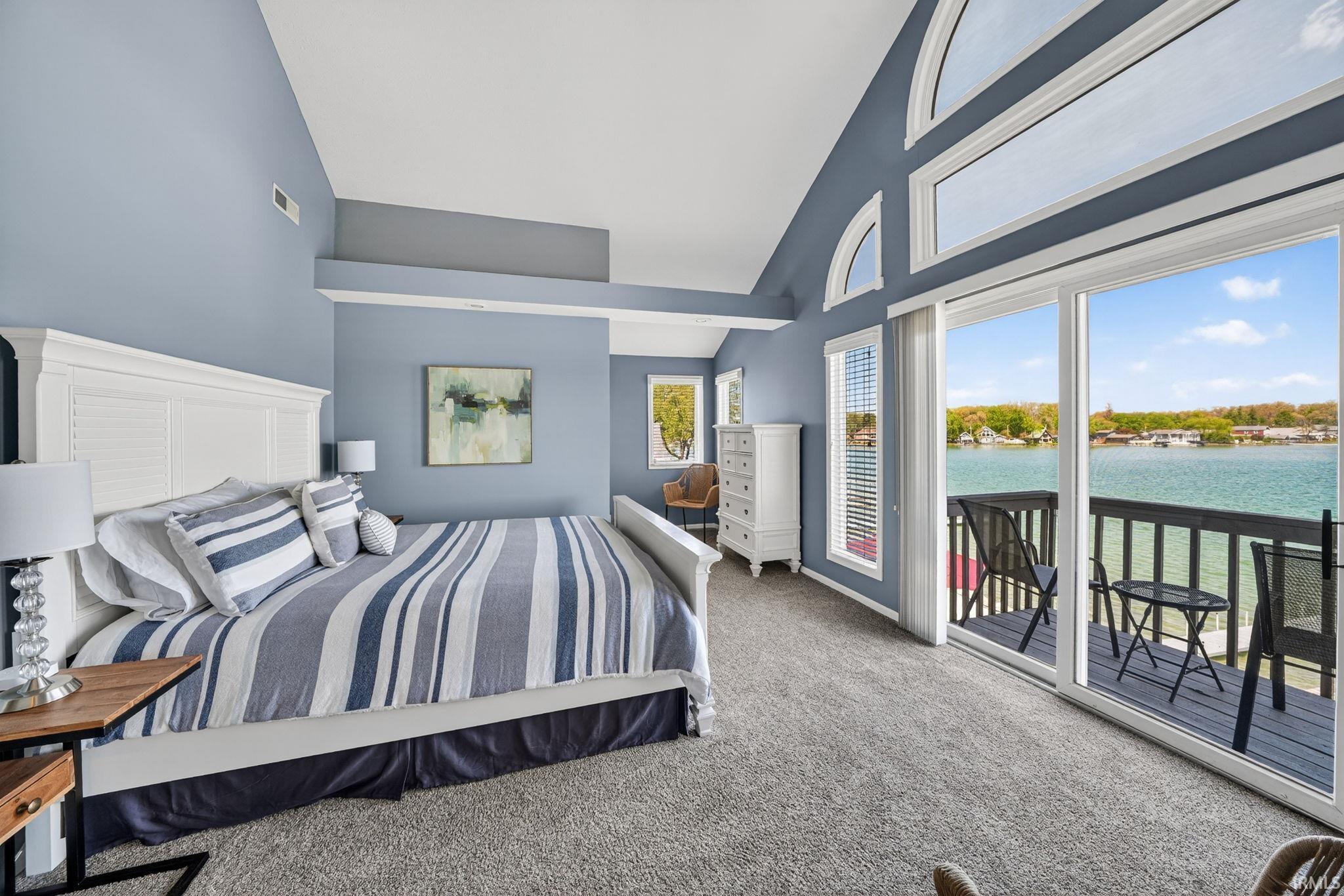 Spacious room featuring vaulted ceilings, a built-in architectural ledge, and expansive windows with arched transoms