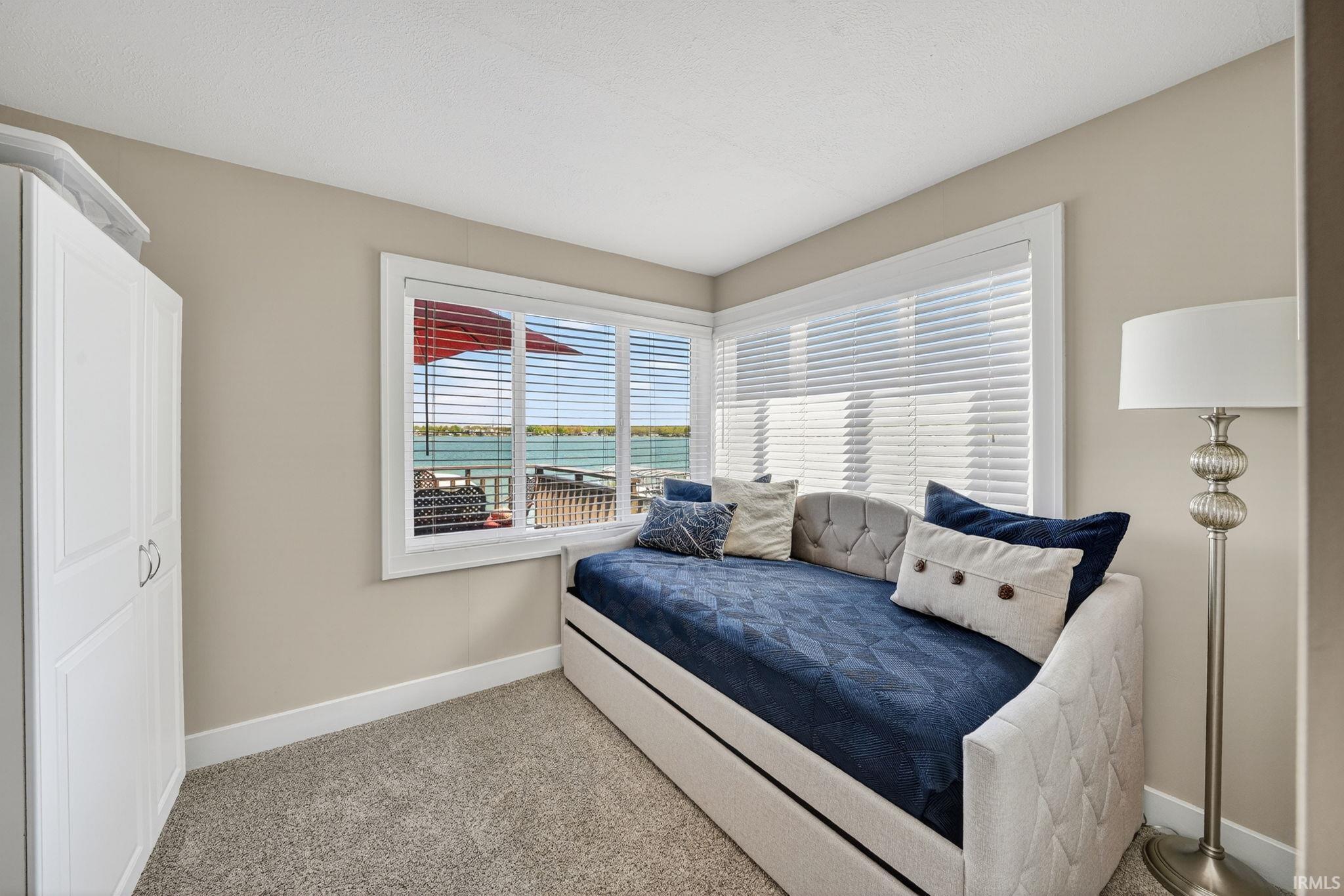 Bright room featuring a large window with white blinds, offering water views