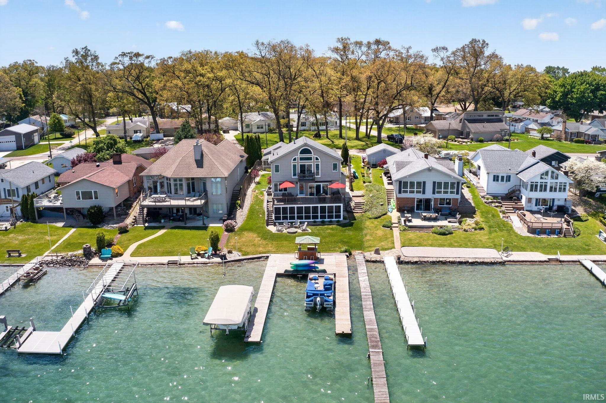 Waterfront property featuring a private dock system, multiple outdoor patio spaces, and a landscaped lawn