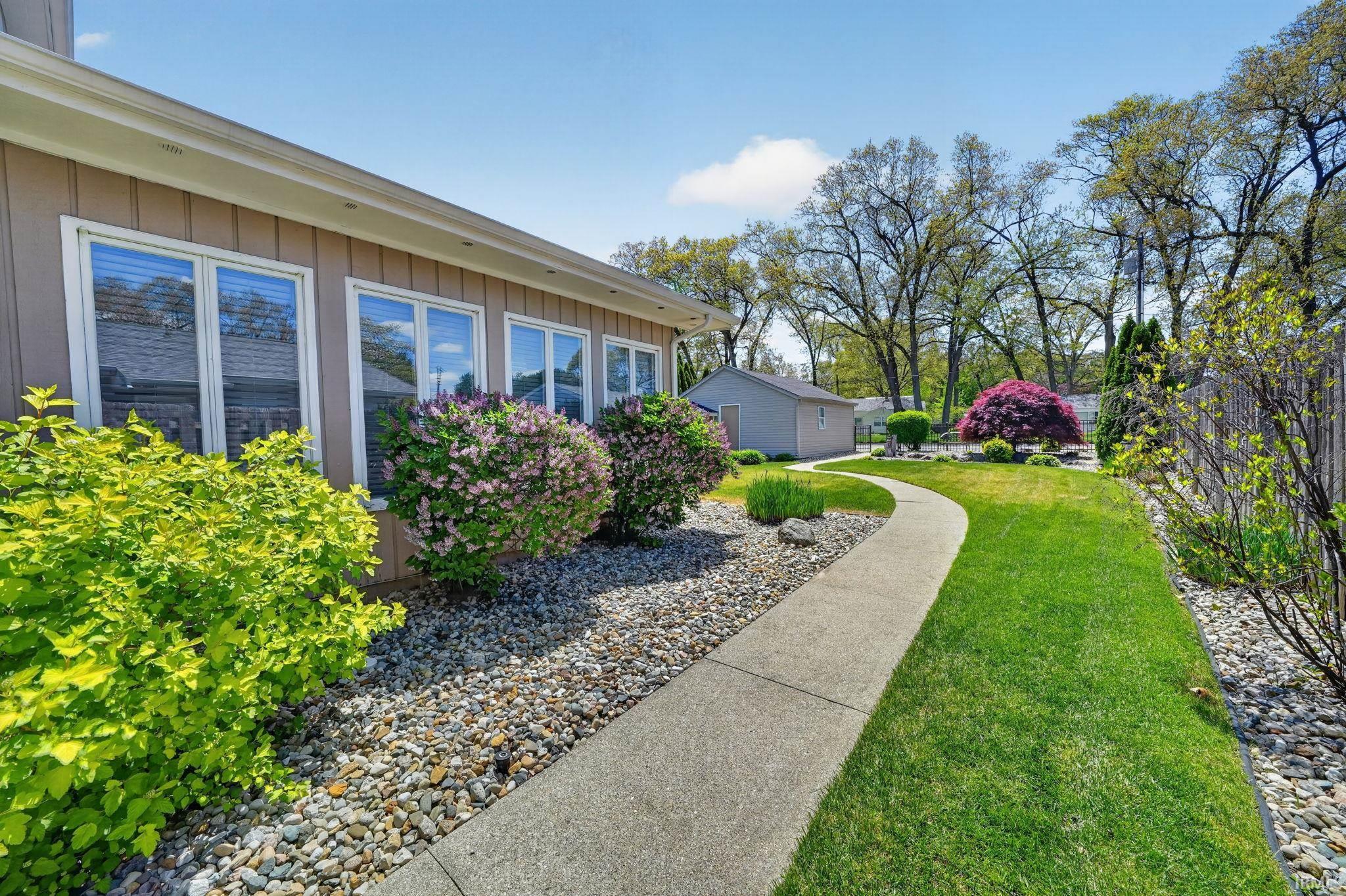 Curved concrete pathway and manicured lawn leading to a rear detached structure