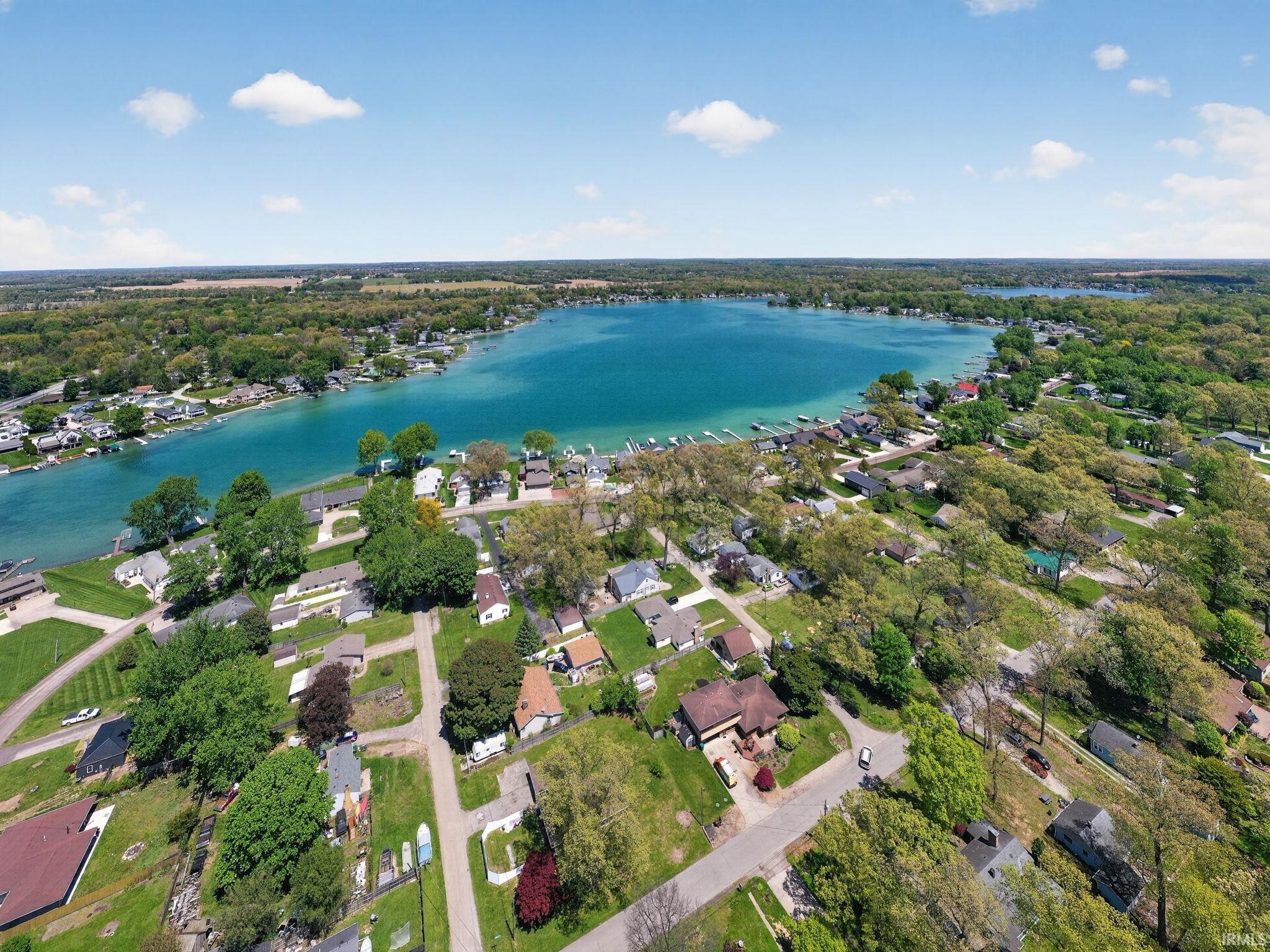 Expansive aerial capturing a lakefront community with homes nestled among mature trees