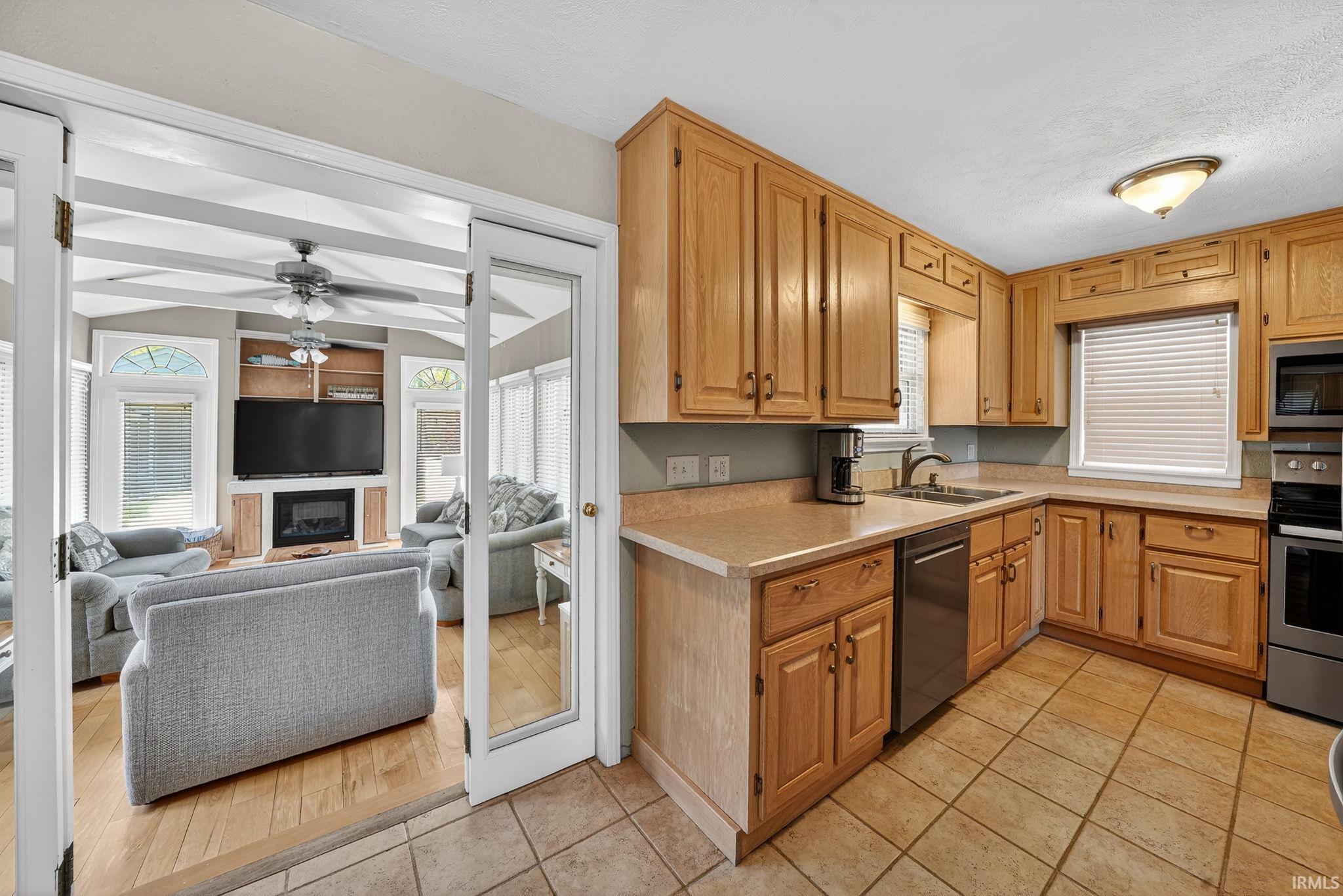 Kitchen featuring light wood cabinetry, a stainless steel dishwasher, a built-in oven, and tile flooring